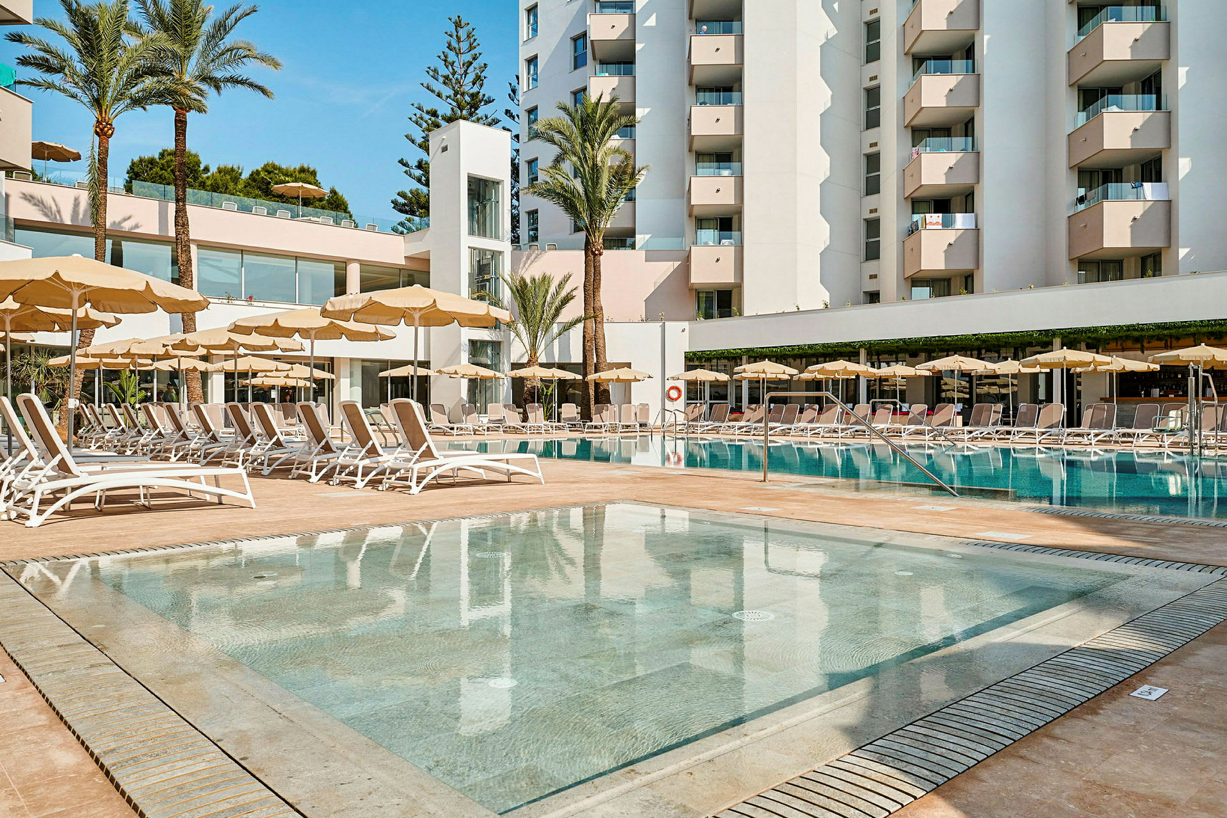 Hotellkompleks med basseng og solsenger. (AI-generert tekst)