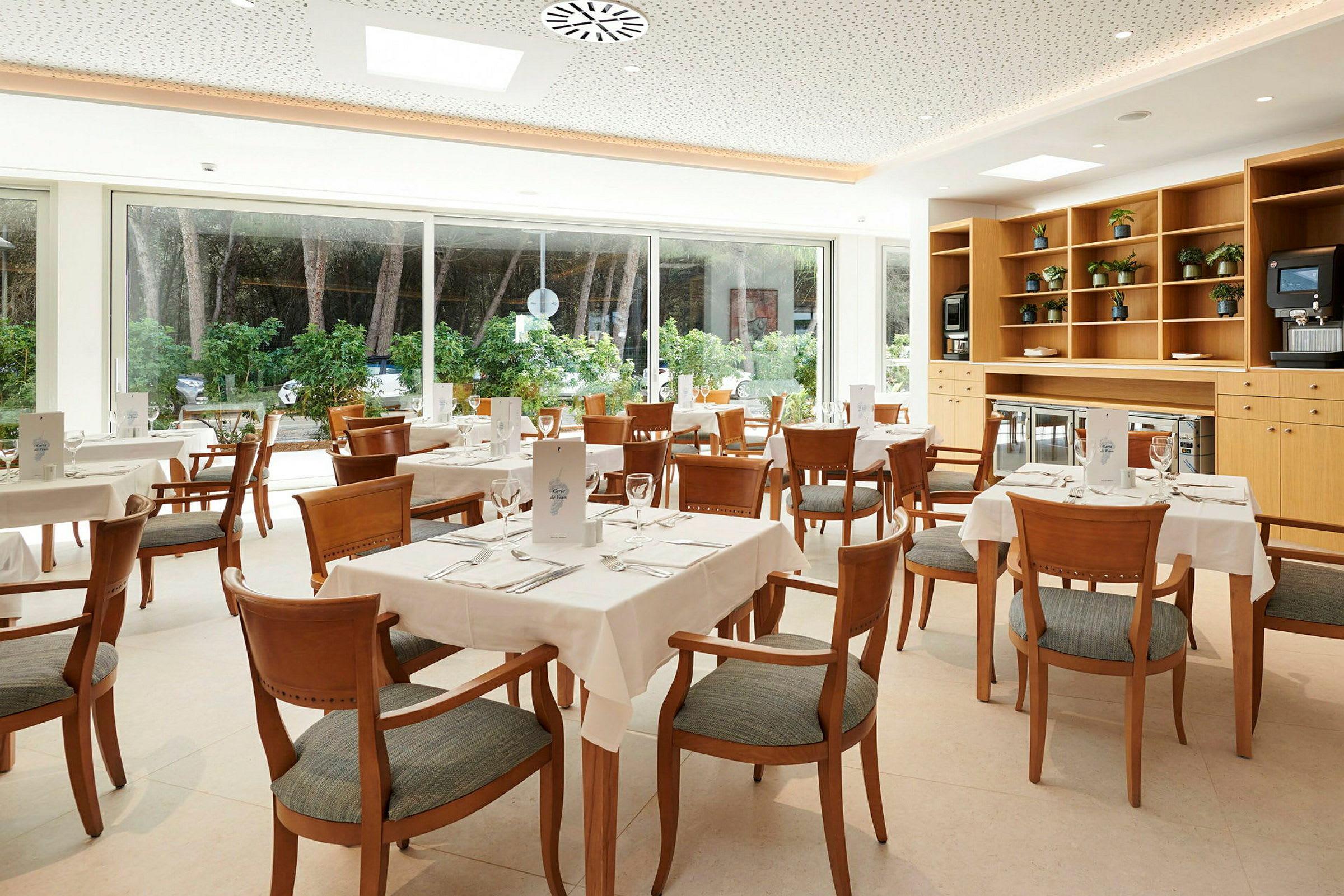 Bilde av en lys restaurant med flere dekkede bord og stoler. (AI-generert tekst)