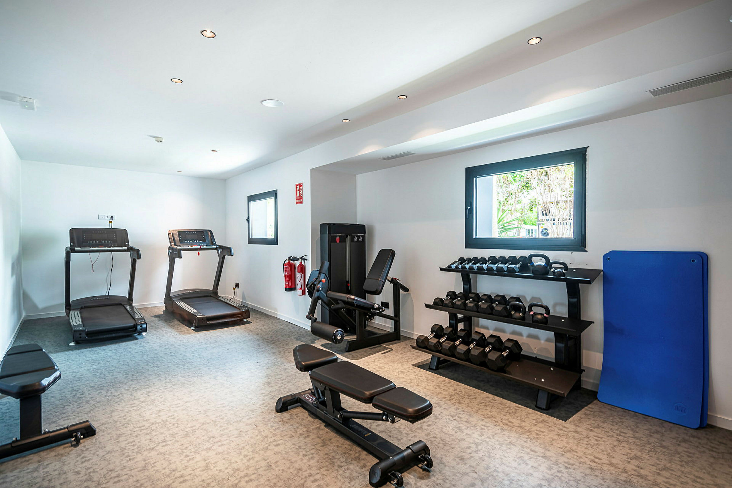Et gym med treningsmaskiner, manualer på hyller og tredemøller. (AI-generert tekst)