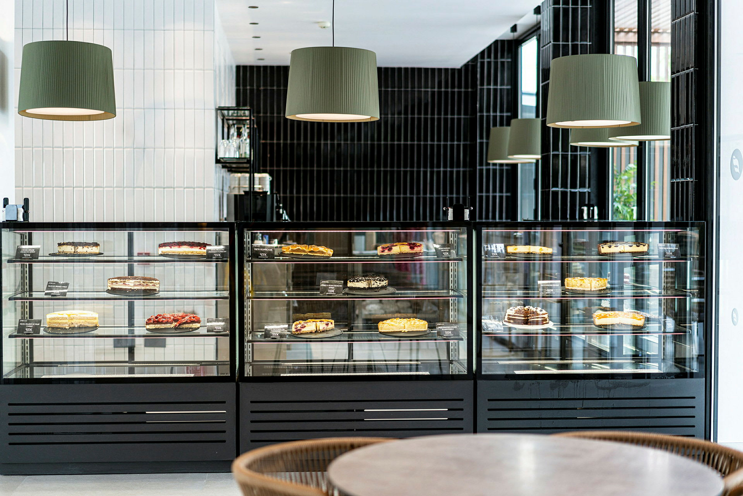 Et glassmonter med ulike kaker som er utstilt for salg i en moderne kafé. (AI-generert tekst)