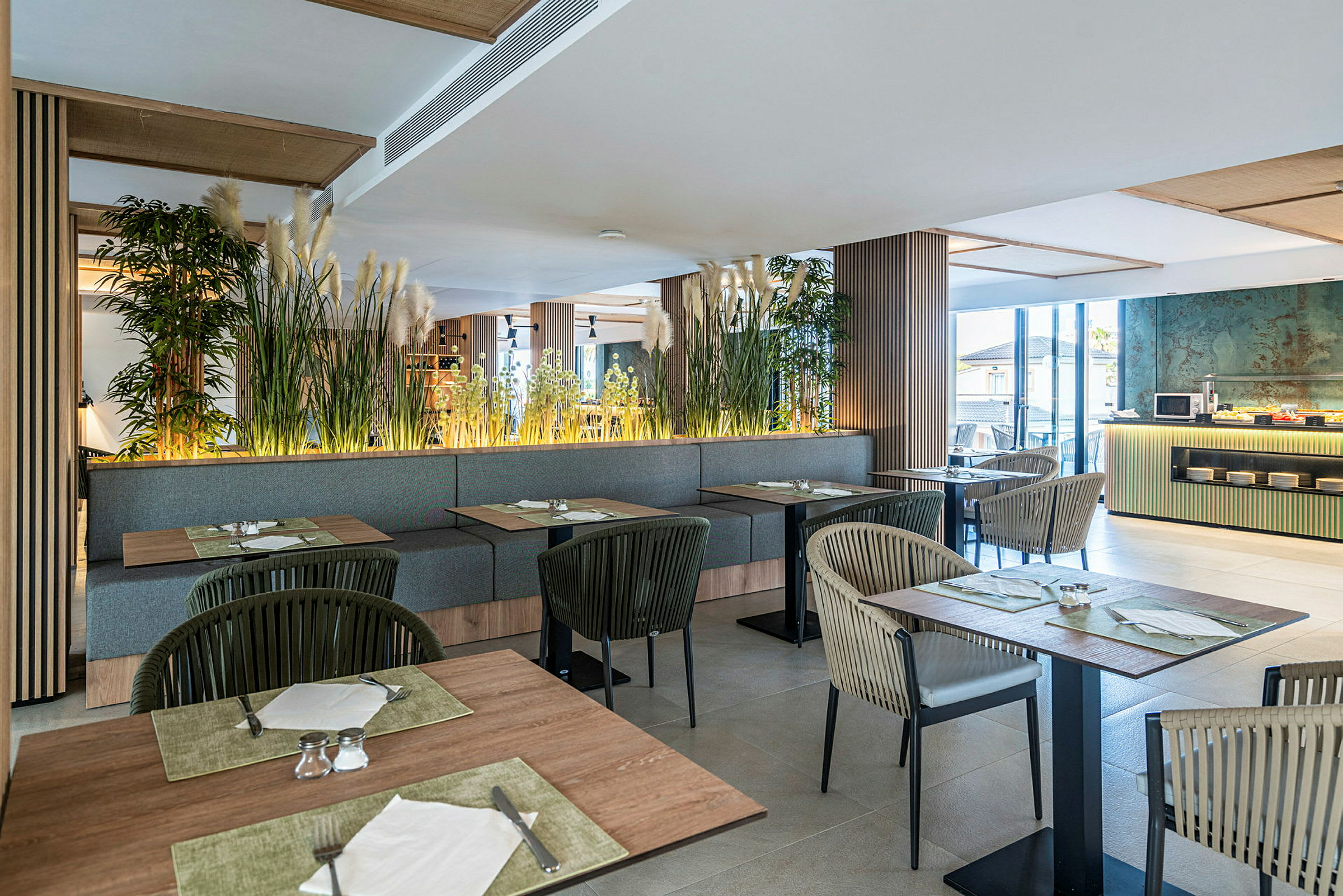 Bilde av en moderne restaurant med sitteplasser, bord og planter som dekorasjon. Vinduer slipper inn naturlig lys. (AI-generert tekst)