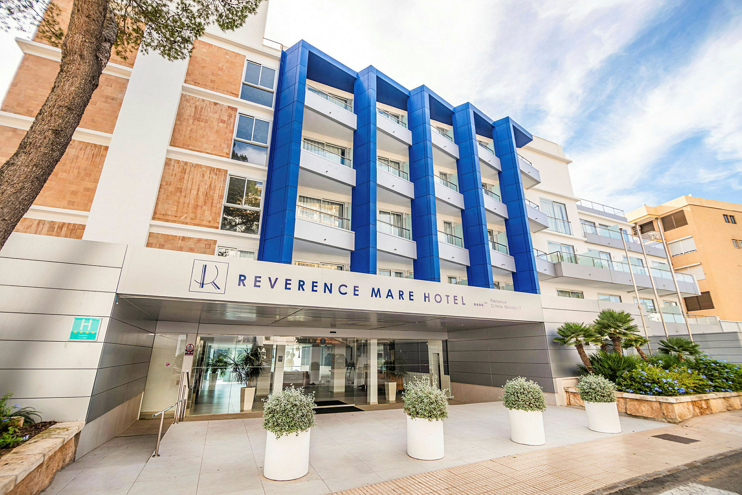 Hotellbygning med skilt som sier "Reverence Mare Hotel". Fasade med blå detaljer og glasbalkonger. (AI-generert tekst)