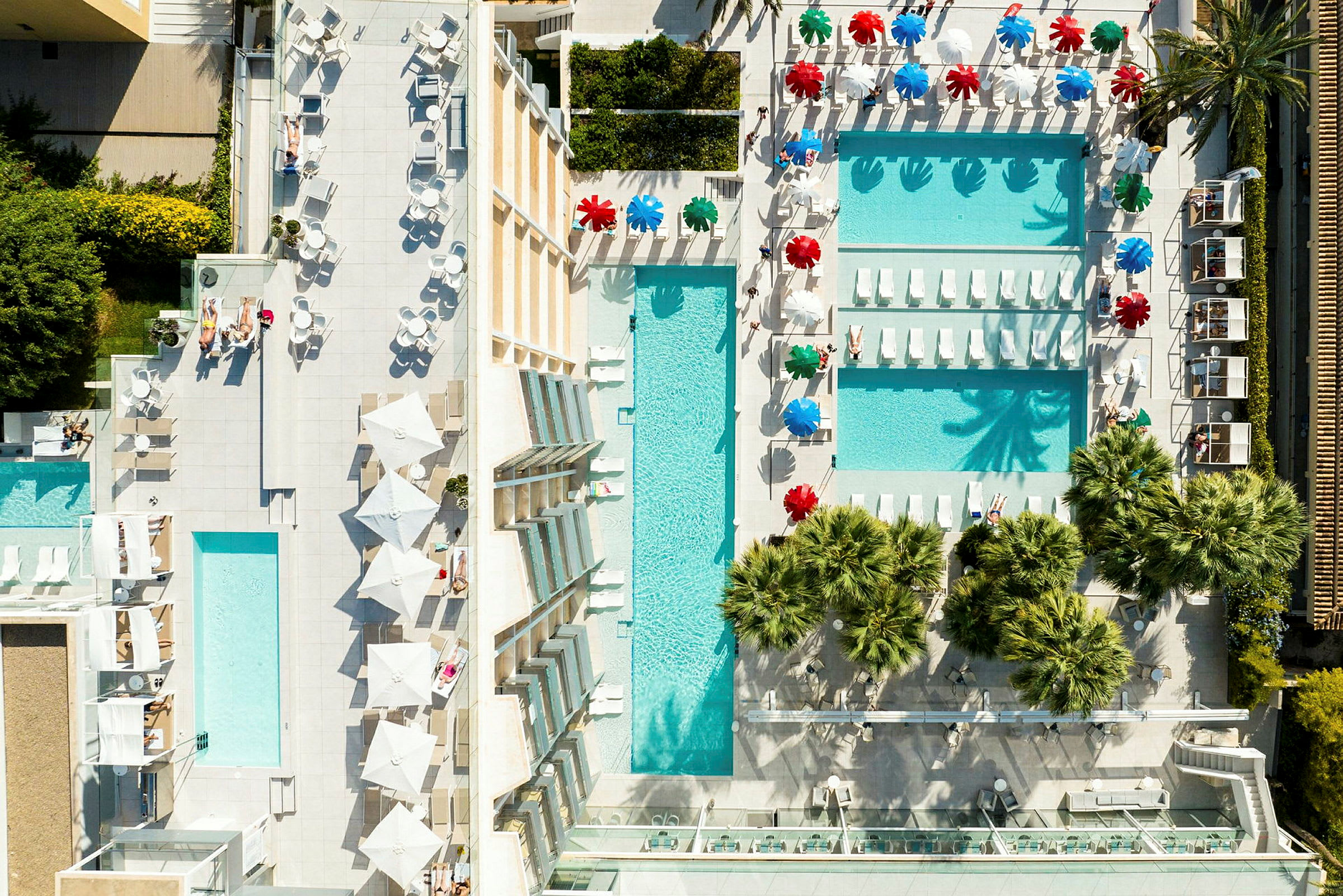 Luftfoto av en resort med bassengområder, solsenger og parasoller. (AI-generert tekst)