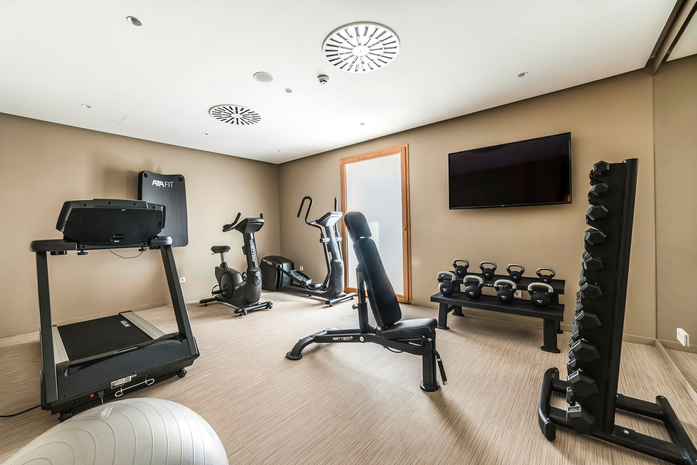 Et treningsrom med treningsmaskiner, manualer og kettlebells. (AI-generert tekst)