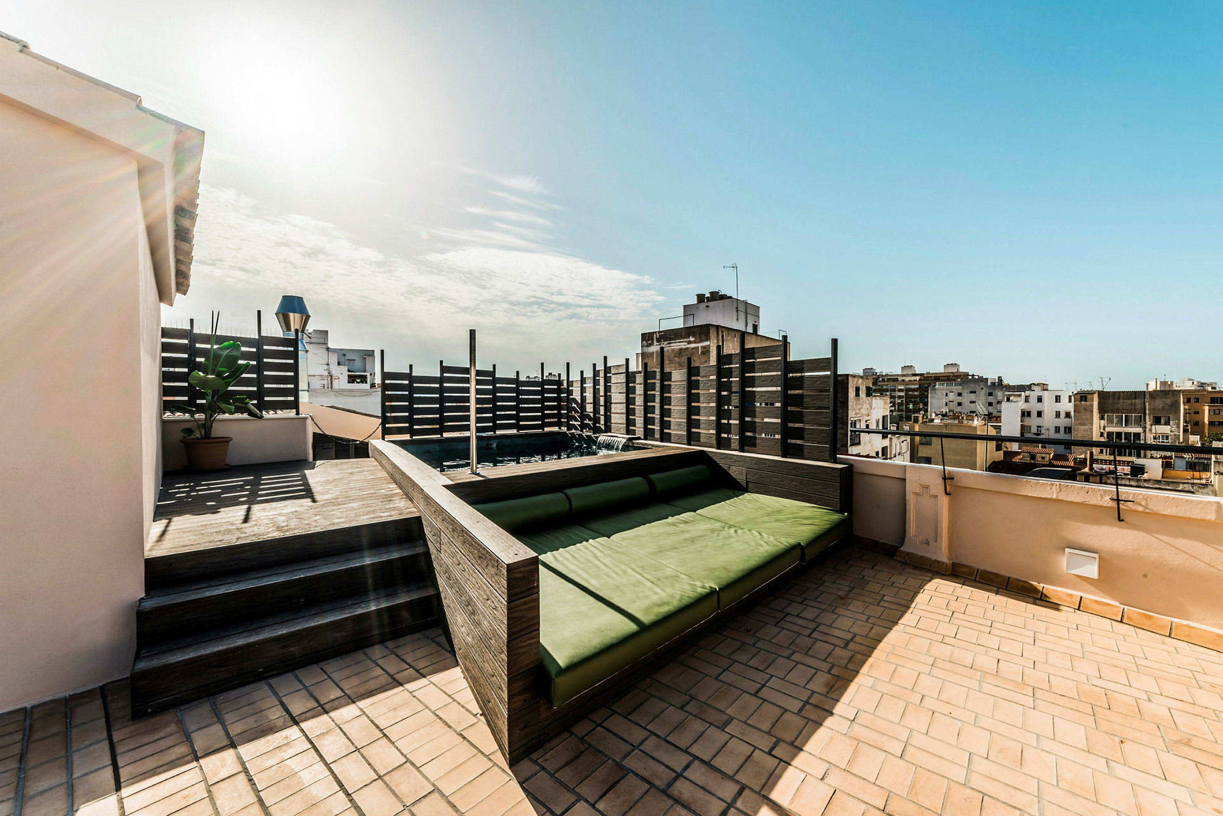En takterrasse med en grønn sitteplass og utsikt over omkringliggende bygninger. (AI-generert tekst)