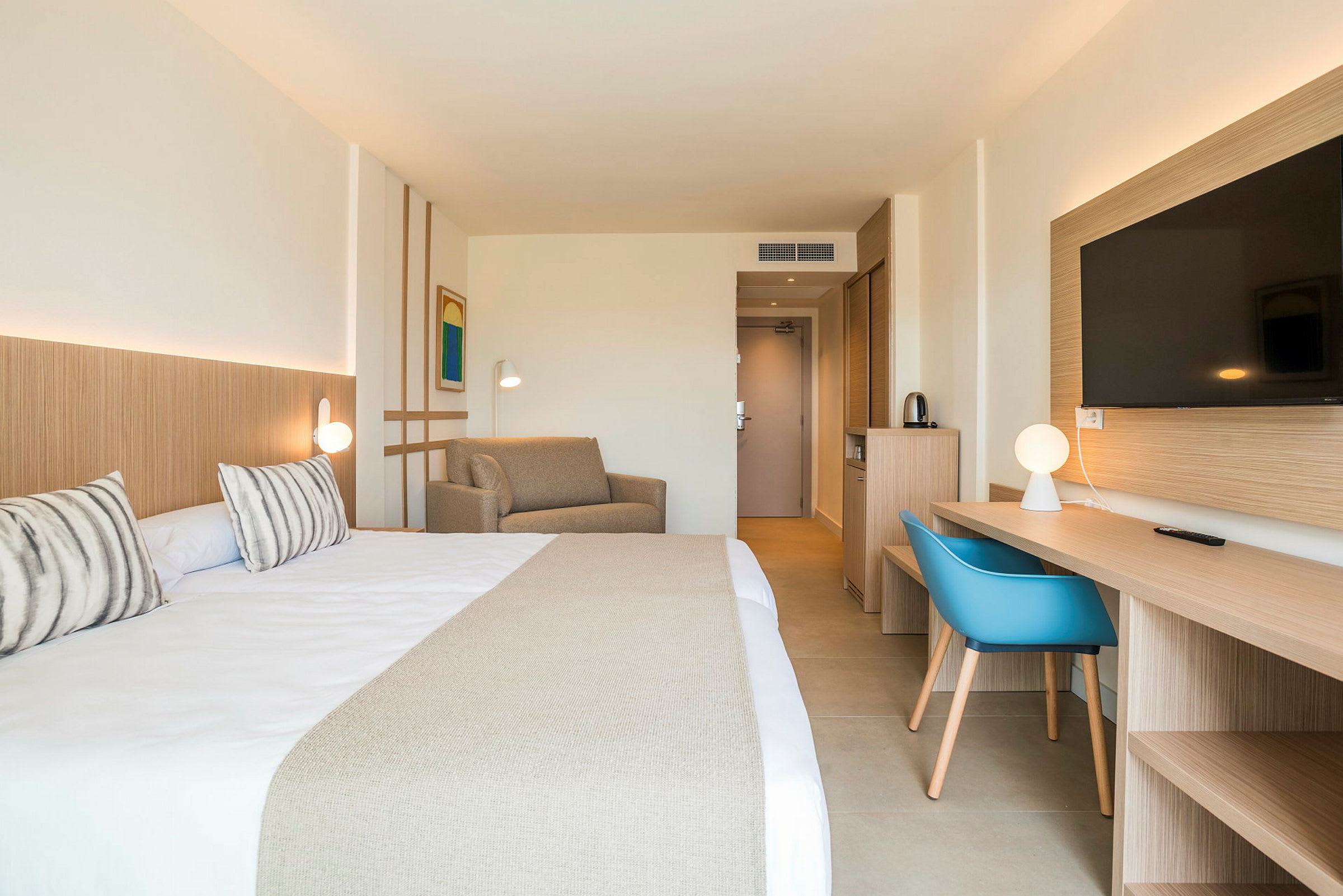 Hotellrom med dobbeltseng, sofa, skrivebord og TV. (AI-generert tekst)