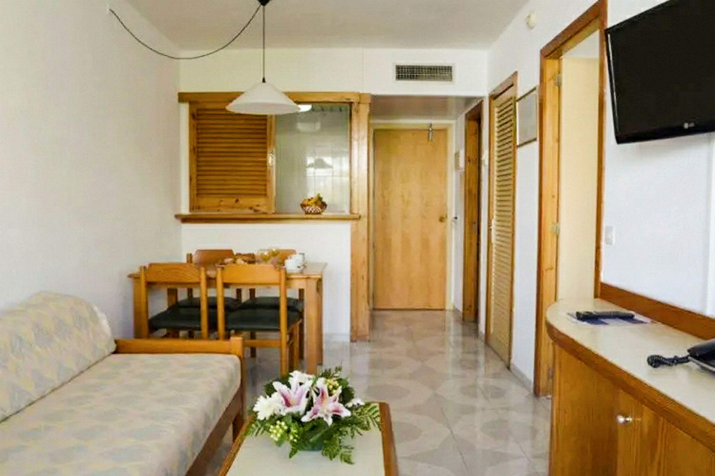 Rommet består av en sittegruppe med sofa og salongbord, en spiseplass med bord og stoler samt en TV på veggen. Det er dører som fører til andre deler av boligen. (AI-generert tekst)