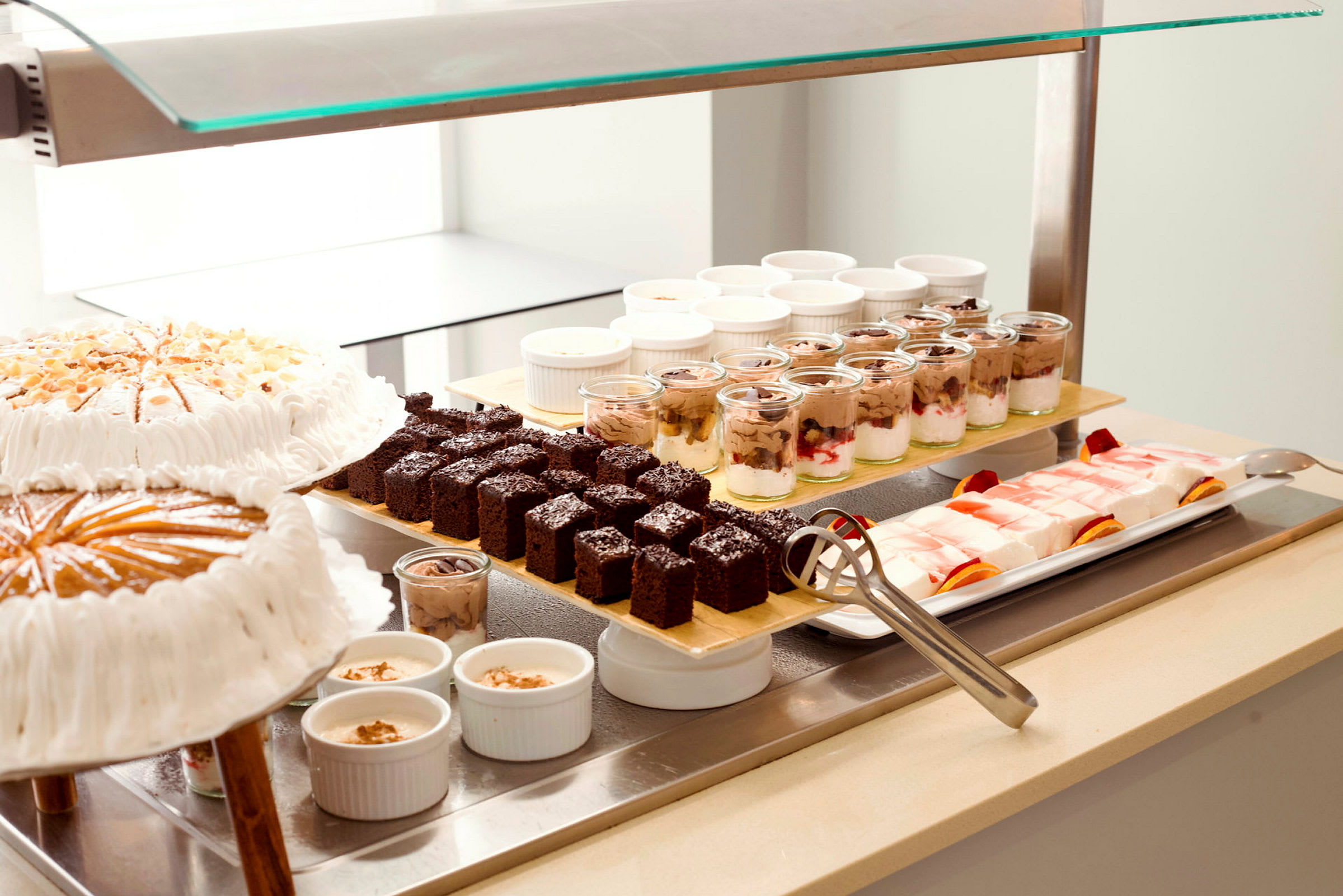Bilde av en buffet med ulike desserter, inkludert kaker, sjokoladekaker, pudding og gelé. (AI-generert tekst)
