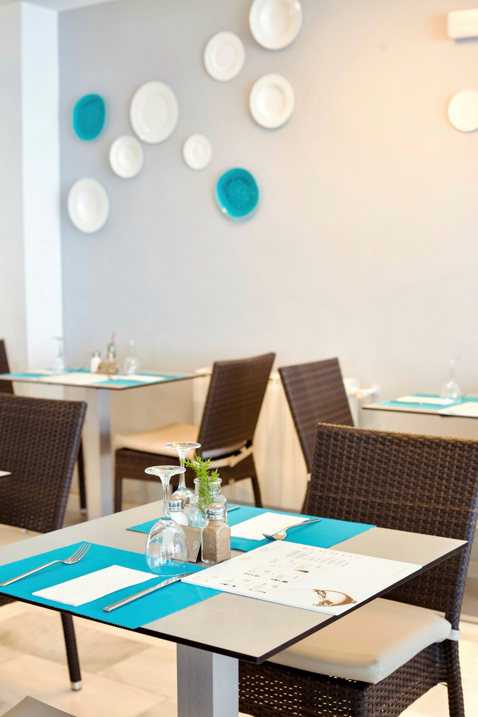 En restaurant med dekkede bord og stoler, med dekorasjoner på veggen. (AI-generert tekst)