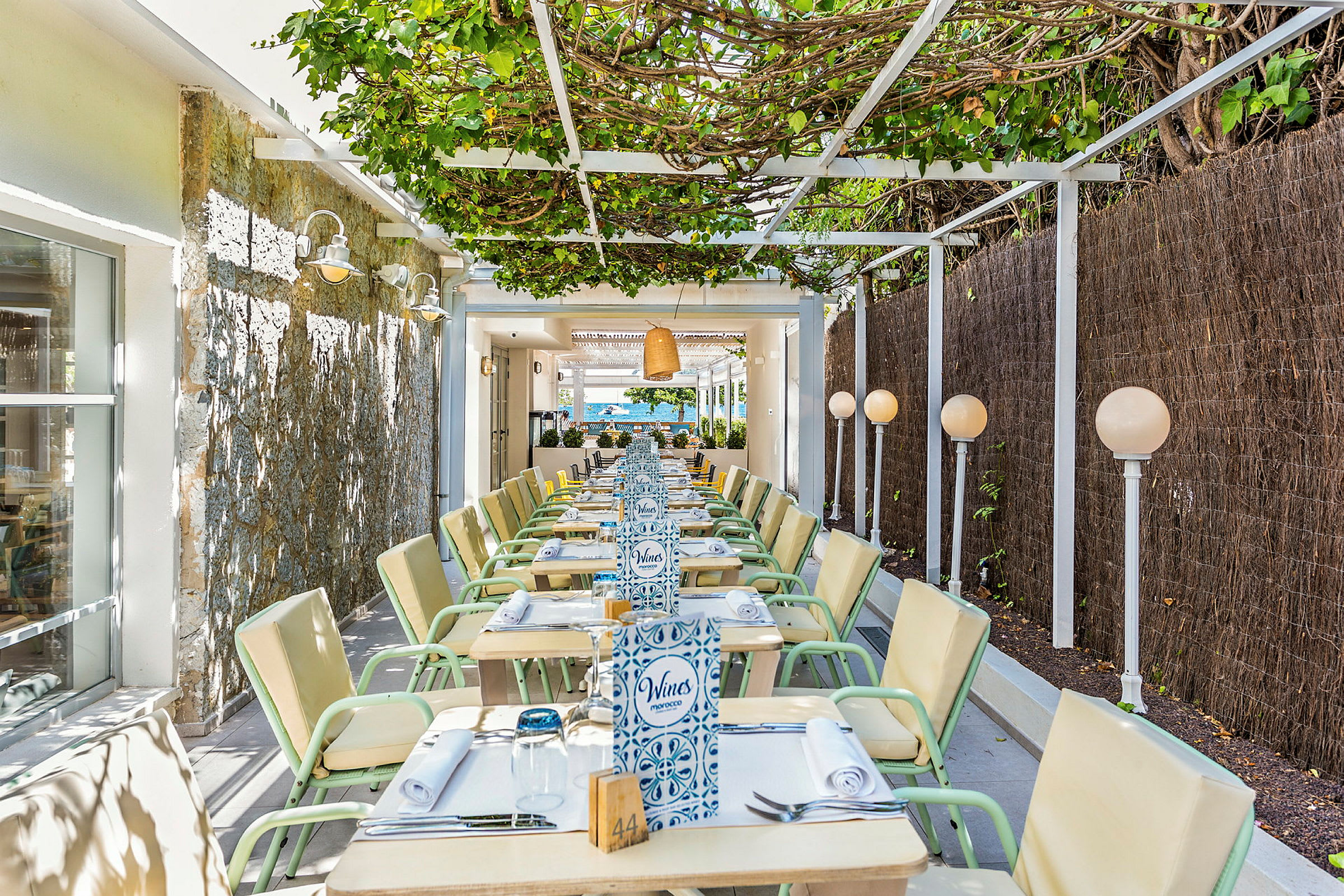 En utendørsrestaurant med sitteplasser under en pergola. (AI-generert tekst)