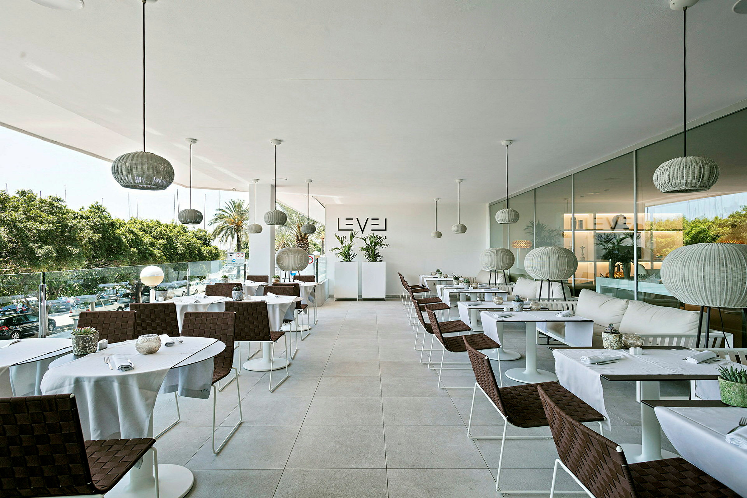 En moderne restaurant med elegante bord og stoler, store glassvinduer og hengende lamper. (AI-generert tekst)