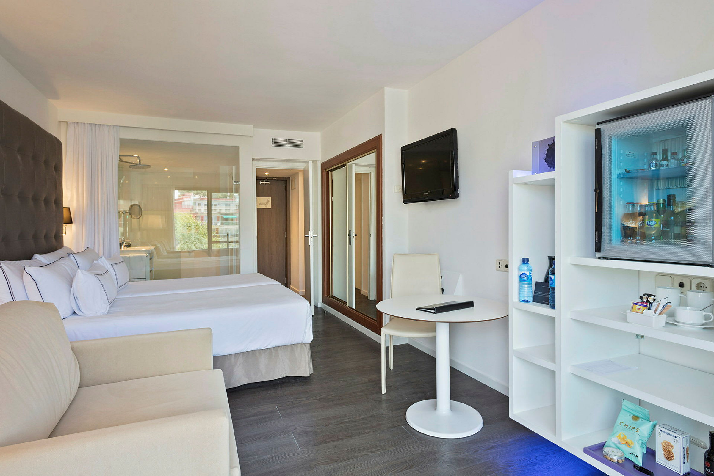 Hotellrom med dobbeltseng, sittemøbler, bord og en minibar. (AI-generert tekst)
