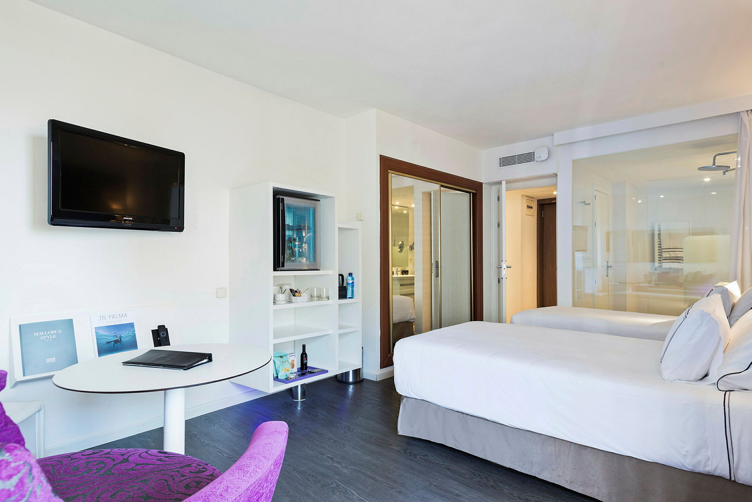 Hotellrom med to senger, TV på veggen og bord med stol. (AI-generert tekst)