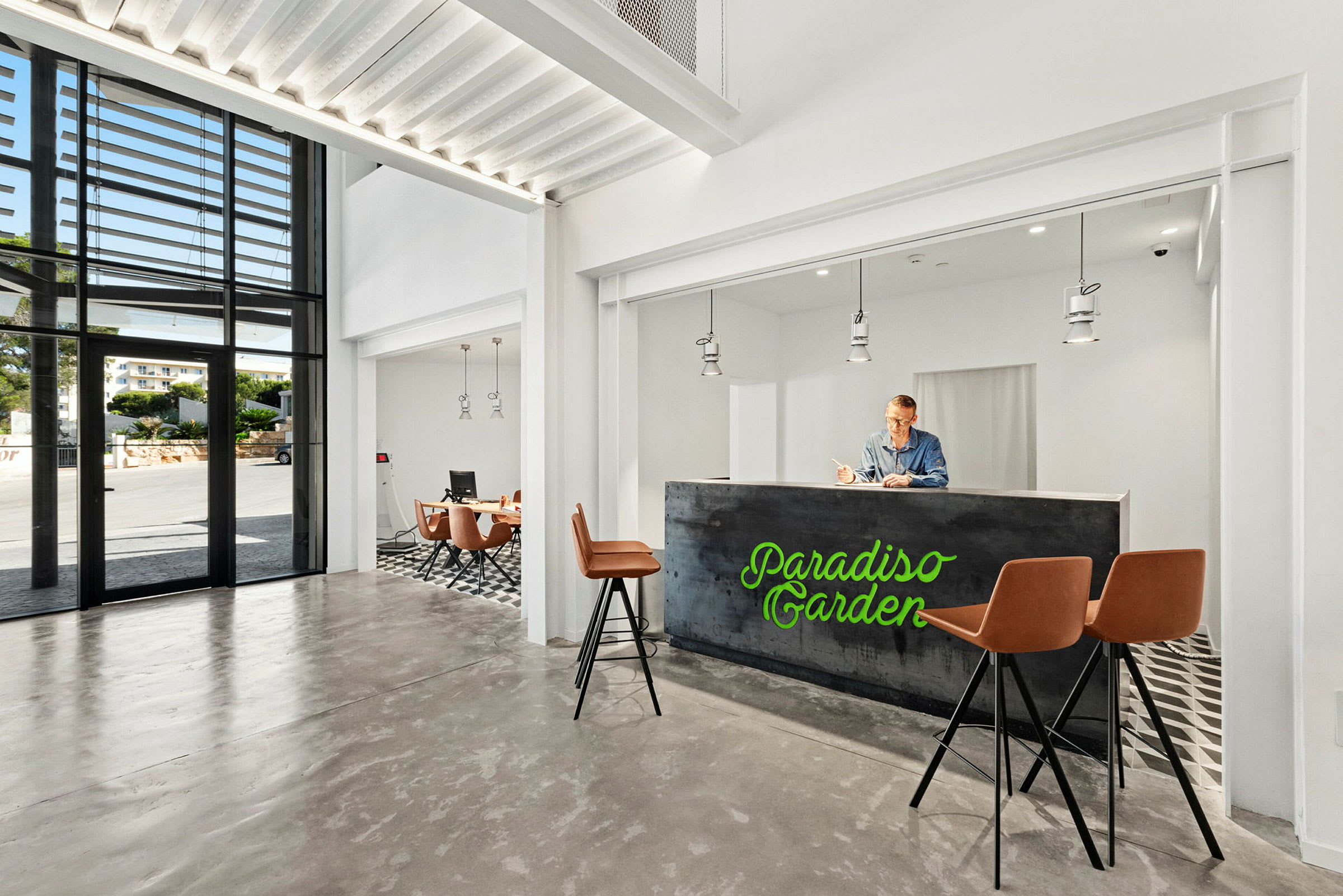 Et moderne hotellobbyområde med resepsjonsdisk, barstoler og et sitteområde i et lyst og luftig miljø. (AI-generert tekst)