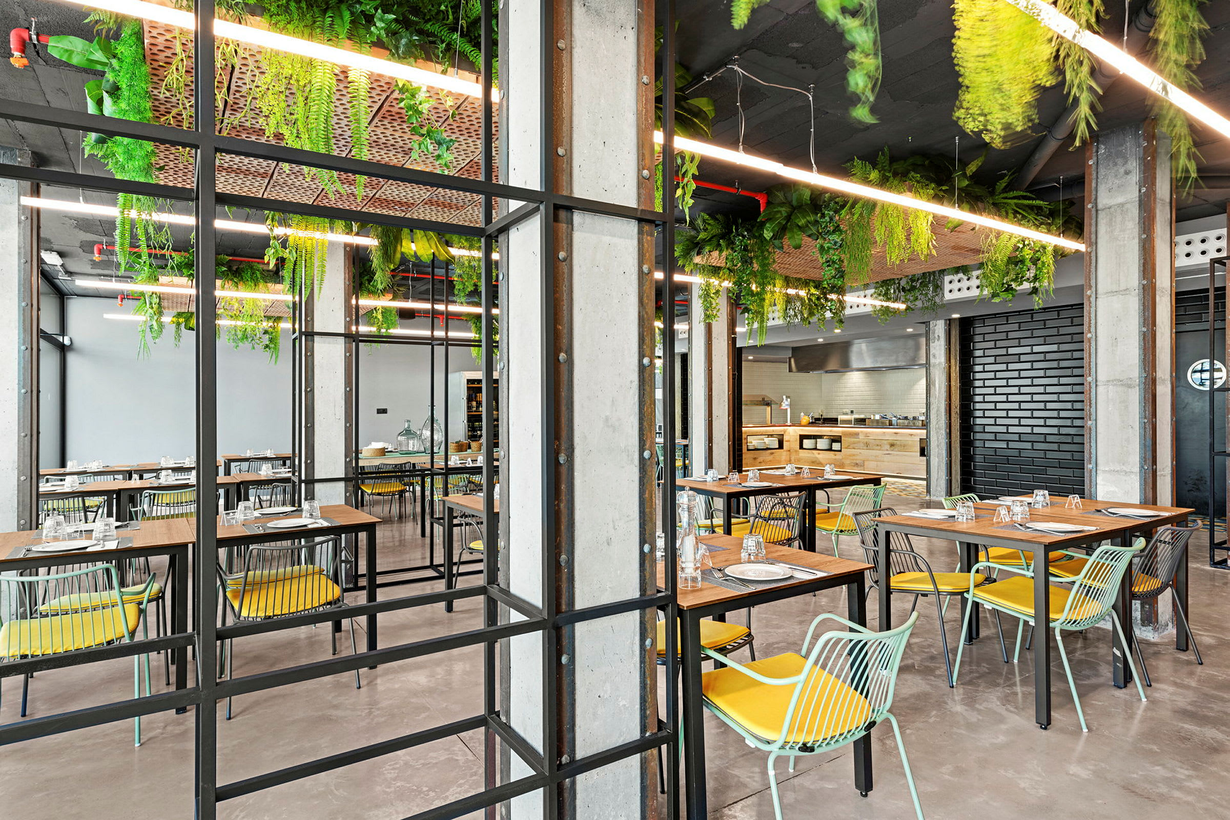En moderne restaurant med bord, stoler og planter som henger fra taket. (AI-generert tekst)