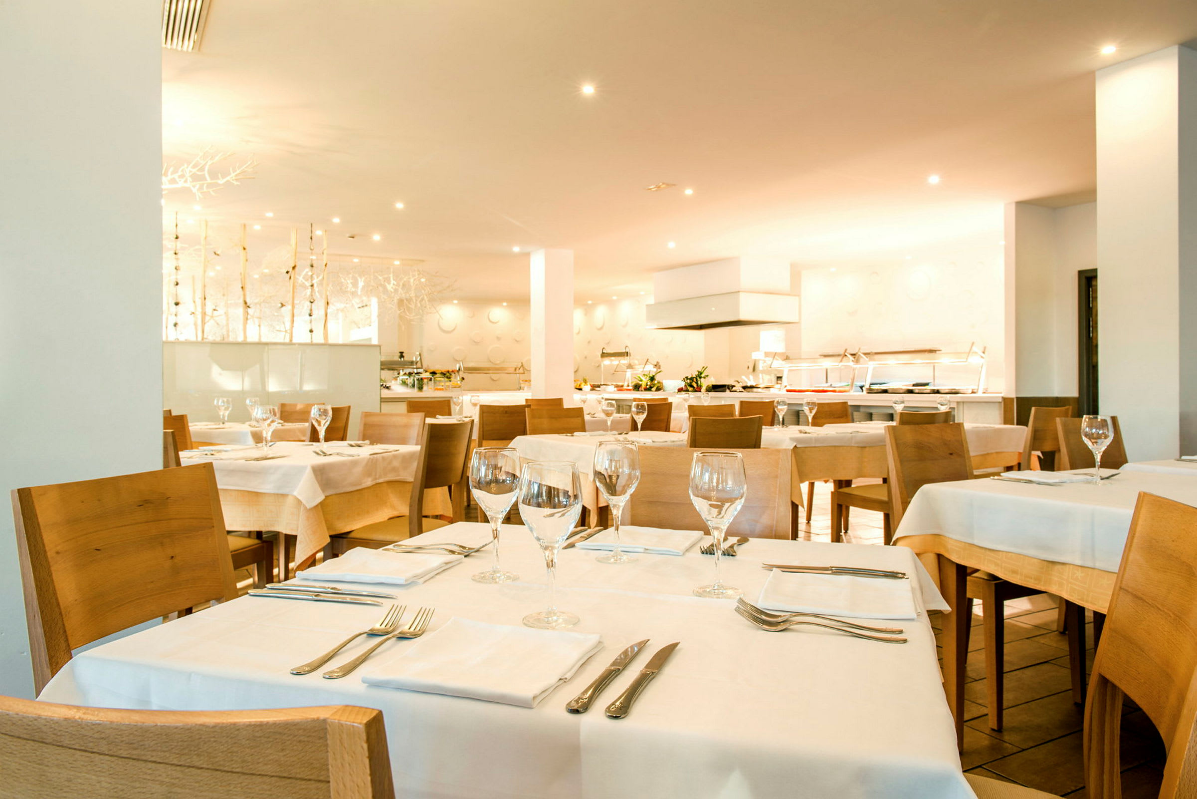 En restaurantinteriør med flere dekkede bord og trestoler. (AI-generert tekst)