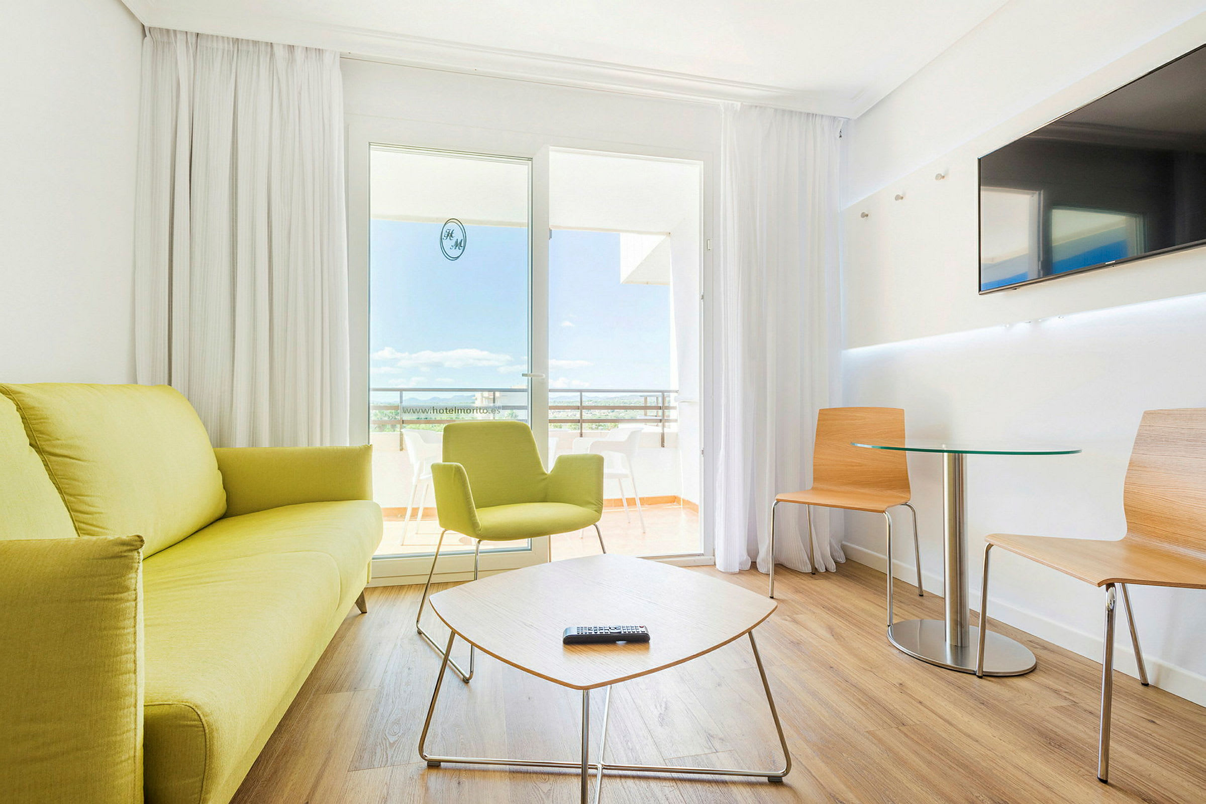 Et moderne hotellrom med lyse møbler og sittegruppe. (AI-generert tekst)
