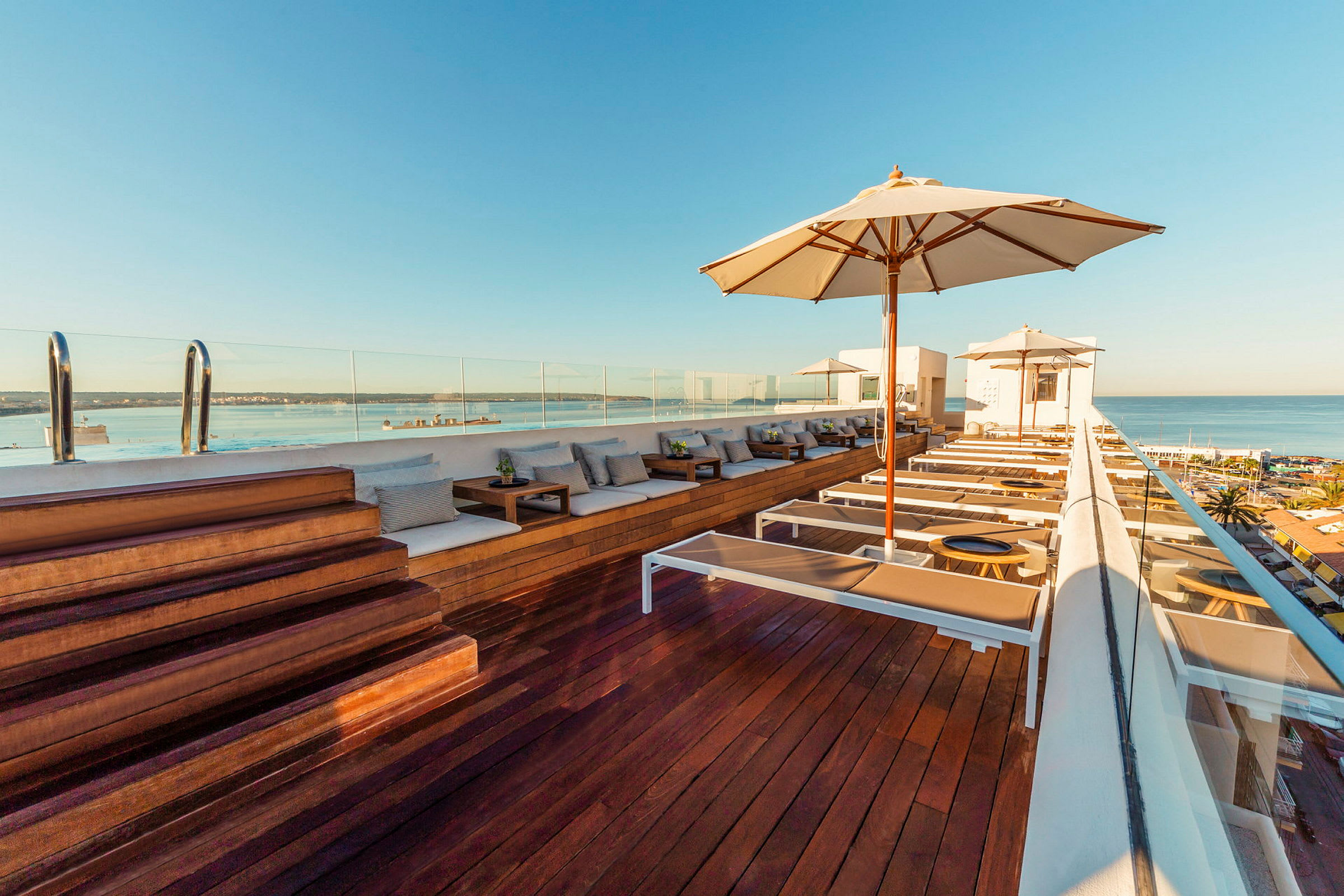 Takterrasse med solsenger, parasoller og utsikt over havet. (AI-generert tekst)