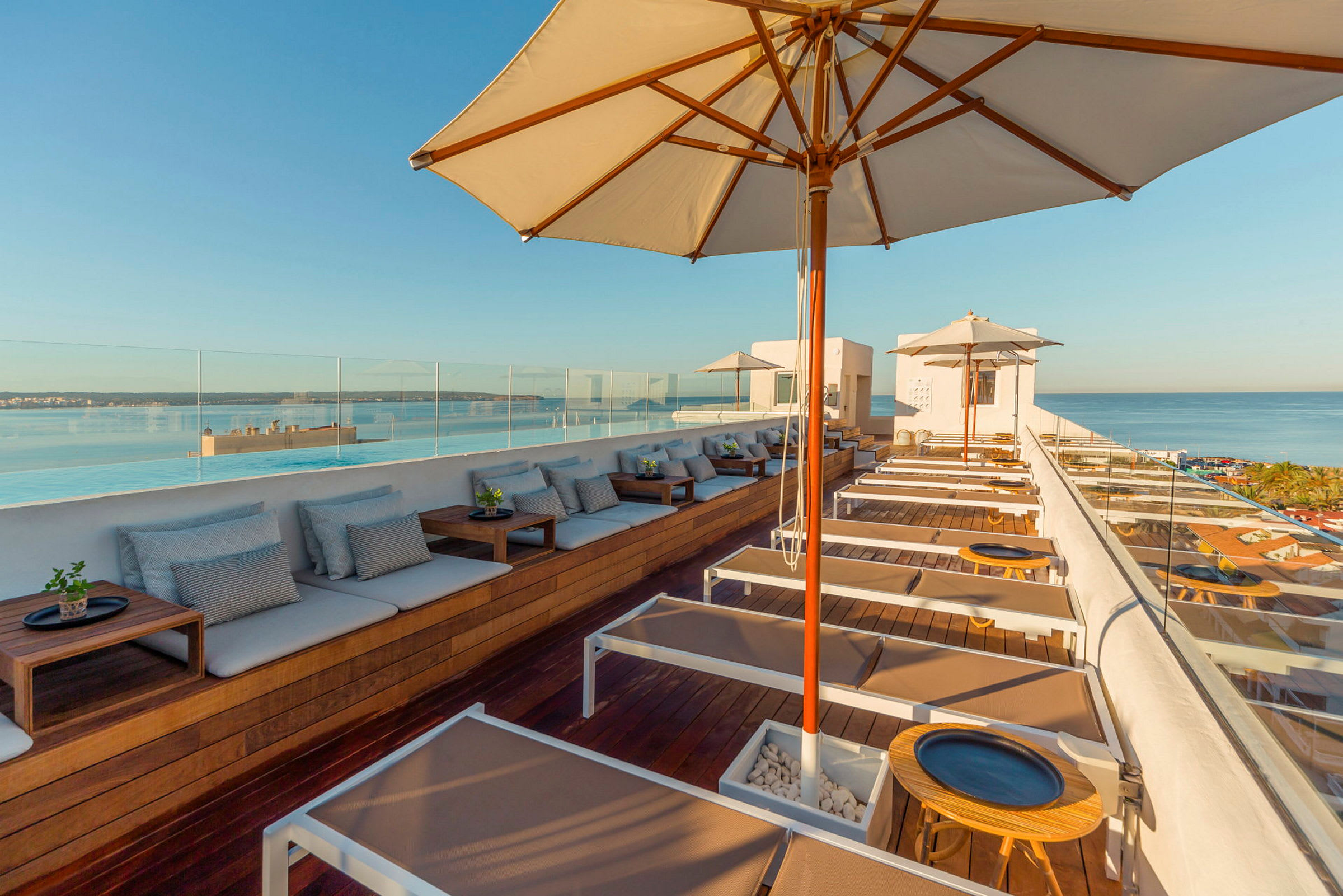Utsikt over en moderne takterrasse med solsenger og parasoller mot havet. (AI-generert tekst)