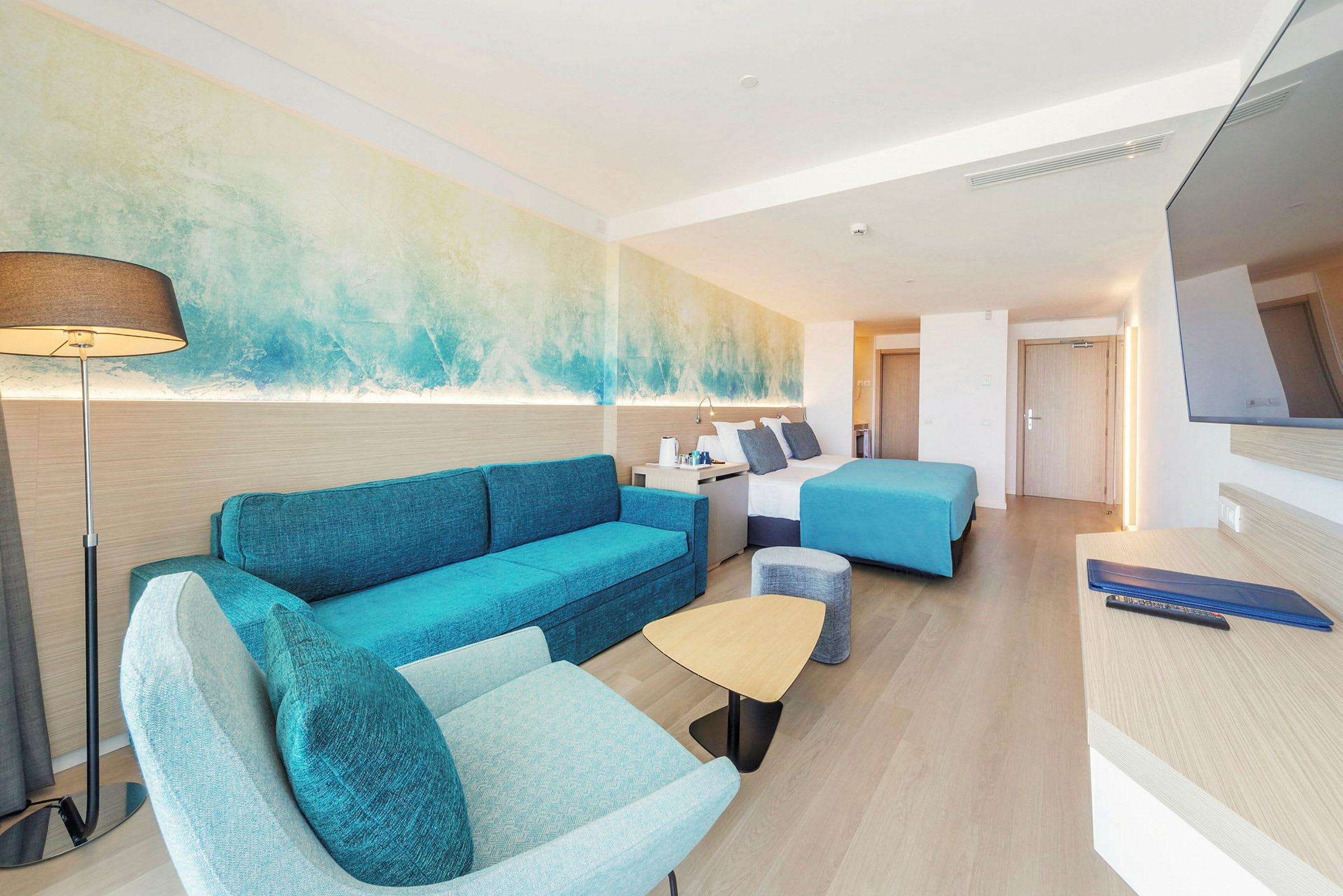 Hotellrom med moderne innredning, blå detaljer og en dobbeltseng. (AI-generert tekst)