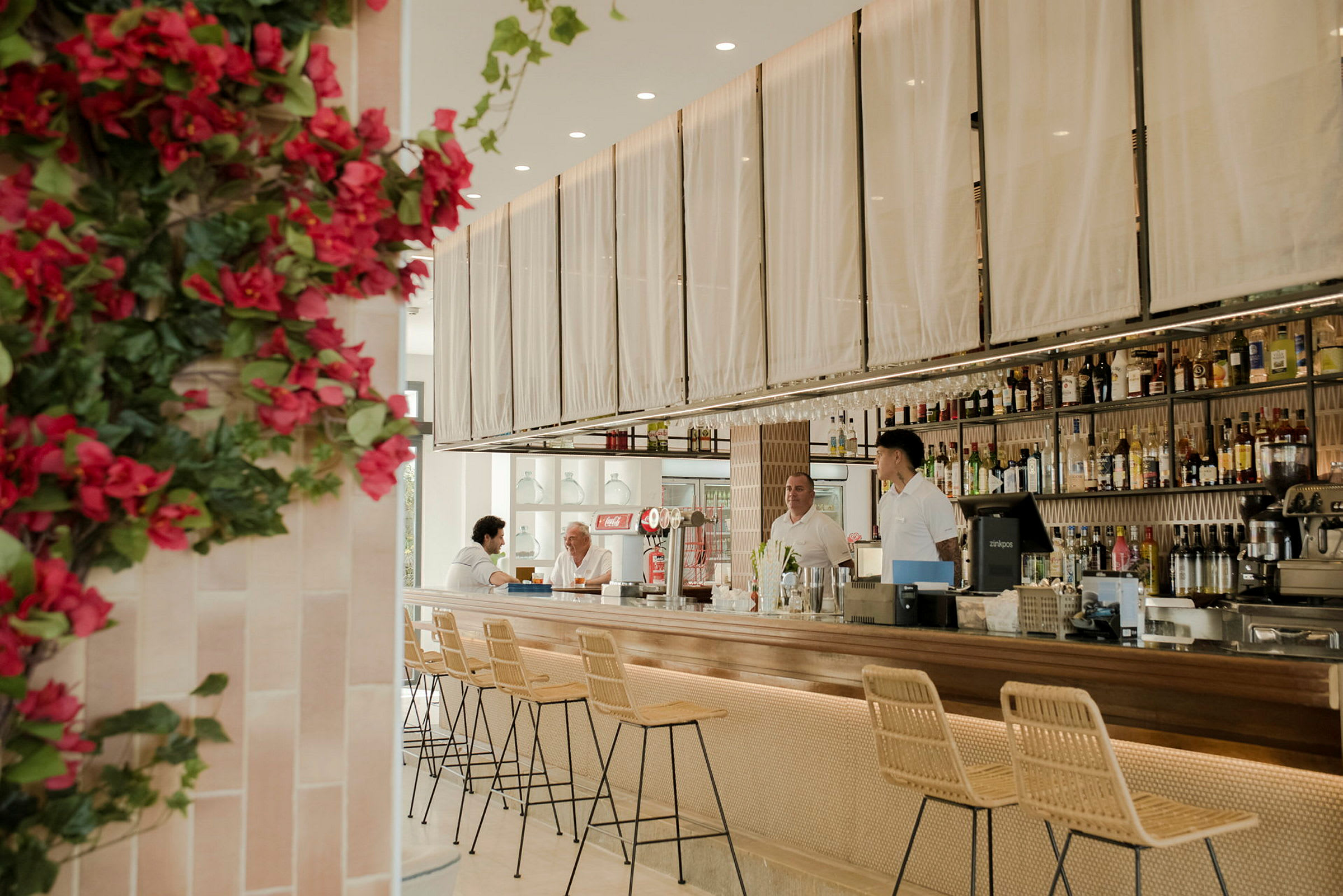 Interiør av en moderne bar med stilfulle møbler og et blomsterkledd hjørne. (AI-generert tekst)