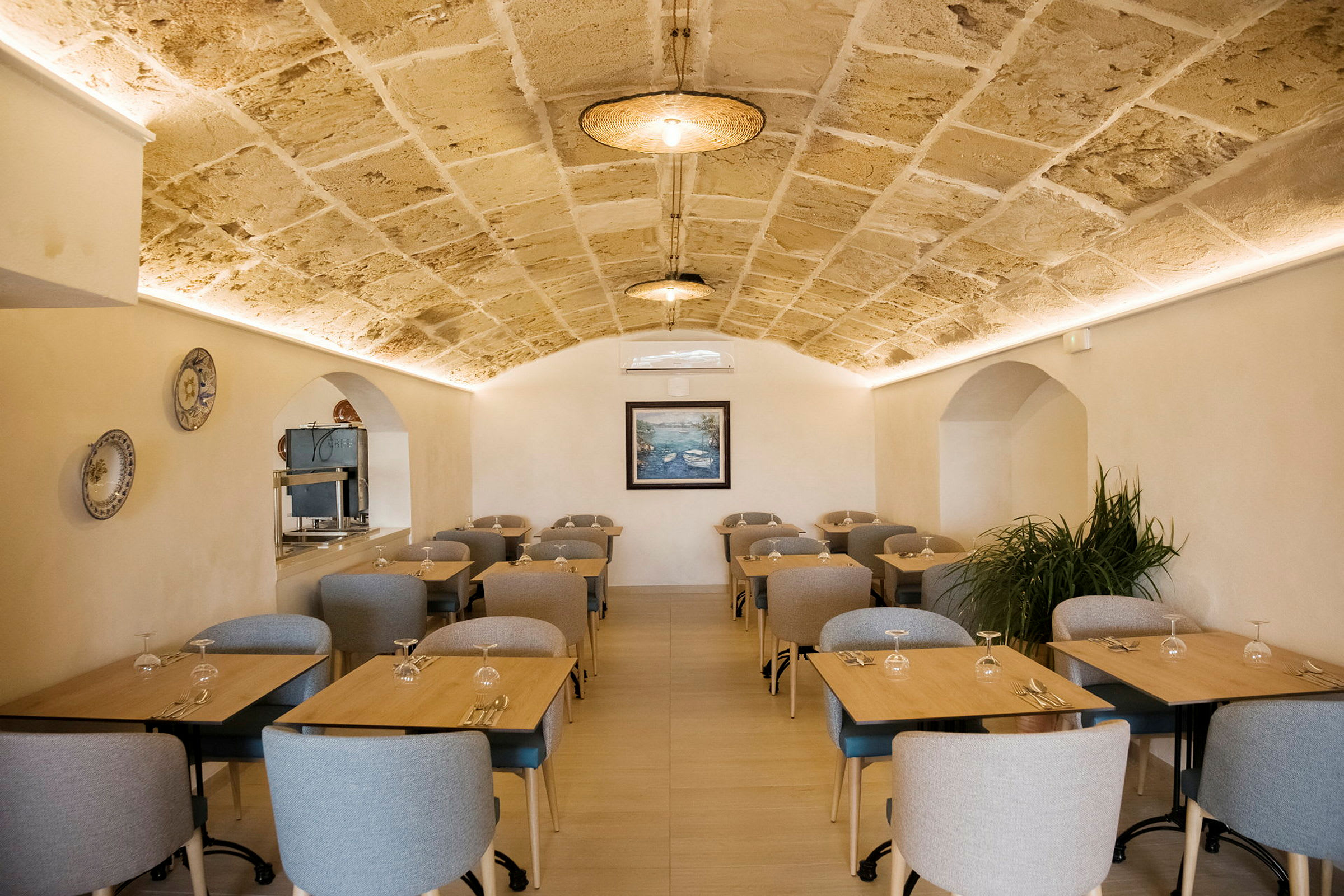 Et restaurantområde med flere bord og stoler, samt et hvelvet tak. (AI-generert tekst)