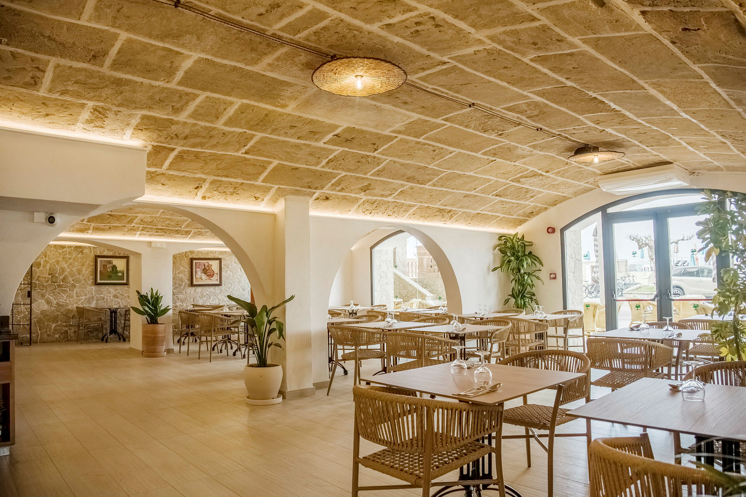 Interiør av en restaurant med steinhvelv, moderne møbler og dekorative planter. (AI-generert tekst)