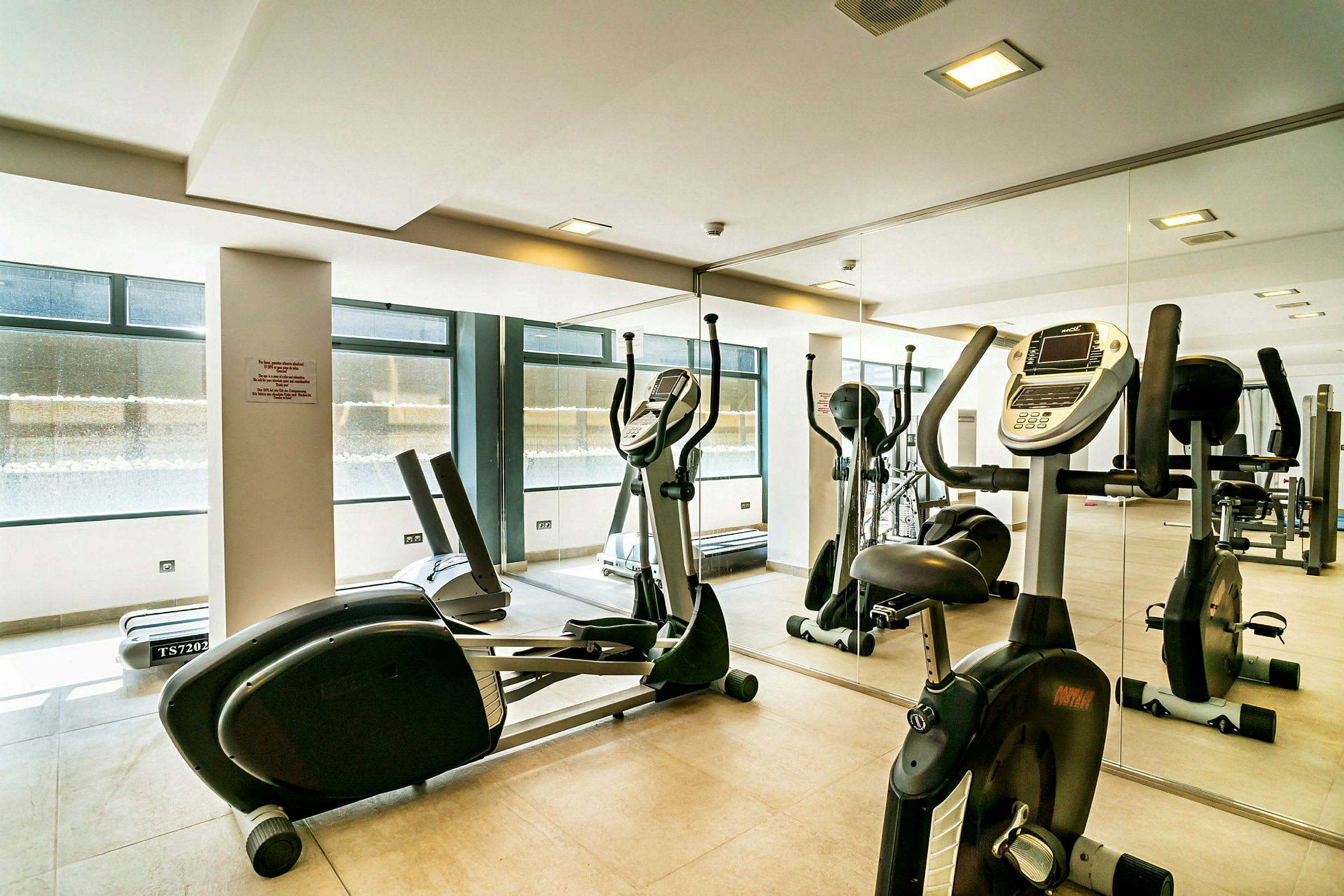 Treningsrom med trimsykler og treningsutstyr foran et speil. (AI-generert tekst)