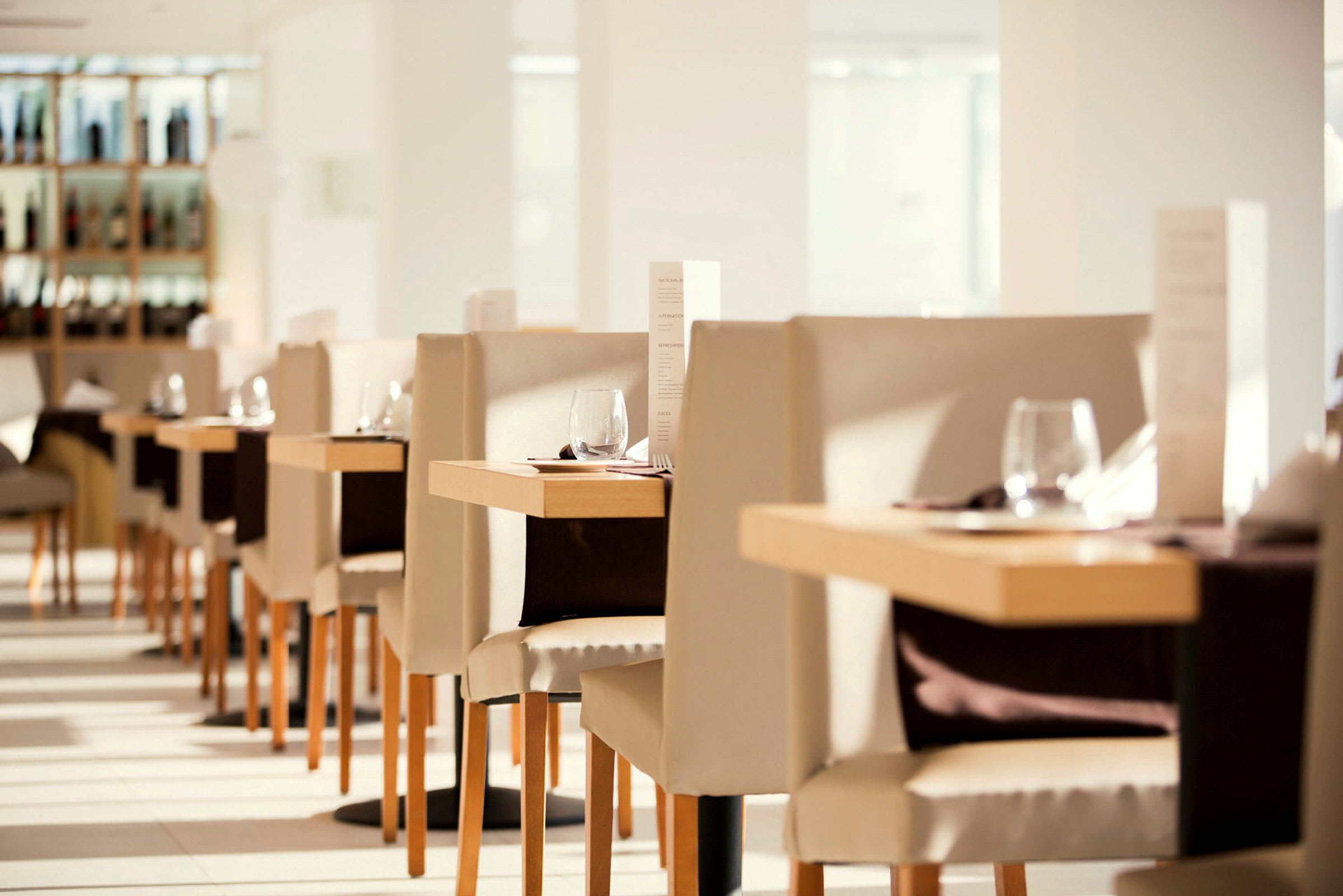 Interiør av en lys og elegant restaurant med dekkede bord og stoler. (AI-generert tekst)