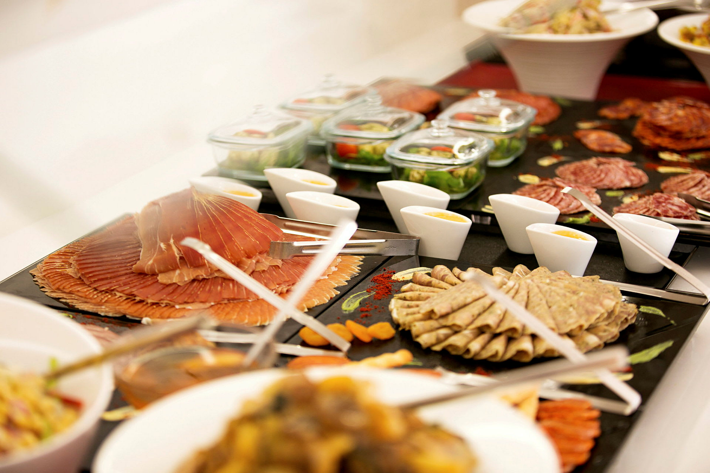 En buffet med ulike kjøttpålegg, salater, sauser og tilbehør presentert på skåler og fat. (AI-generert tekst)