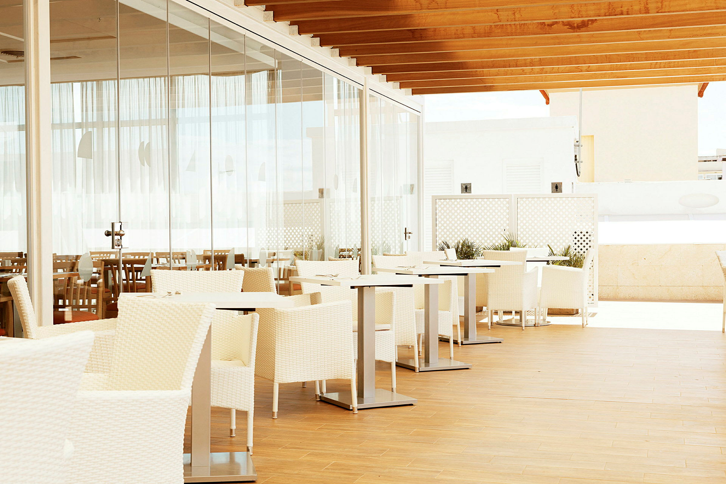 Utendørs restaurant med hvite møbler og glassvegger. (AI-generert tekst)