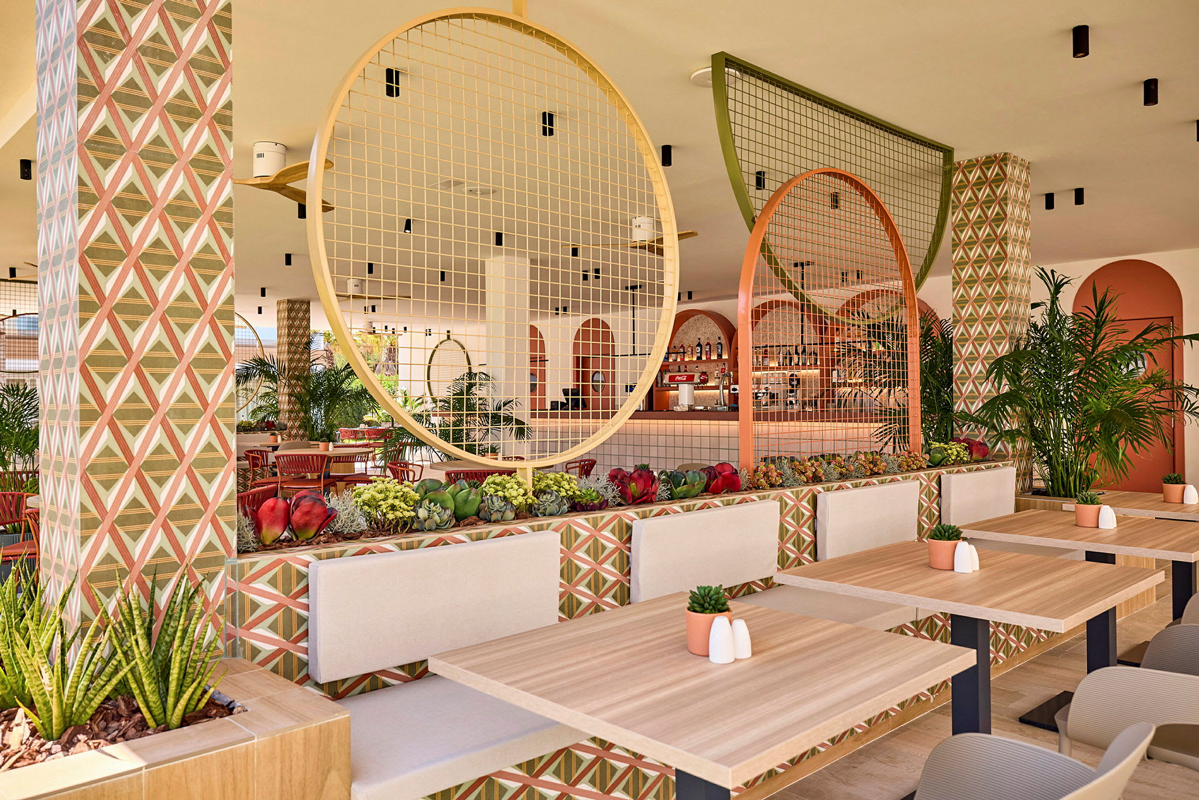 En velutformet restaurant med trebord, geometrisk mønstrede vegger og dekorative sirkulære detaljer. (AI-generert tekst)