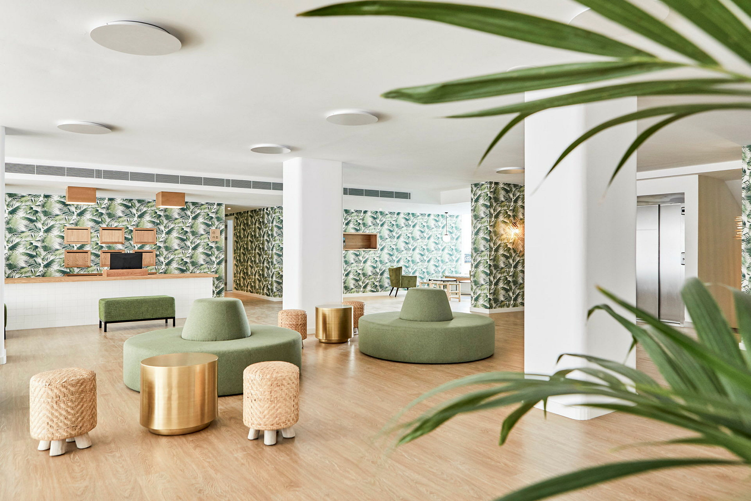 Moderne hotellobby med grønne møbler, vegger dekorert med palmebladmønstre og tredetaljer. (AI-generert tekst)