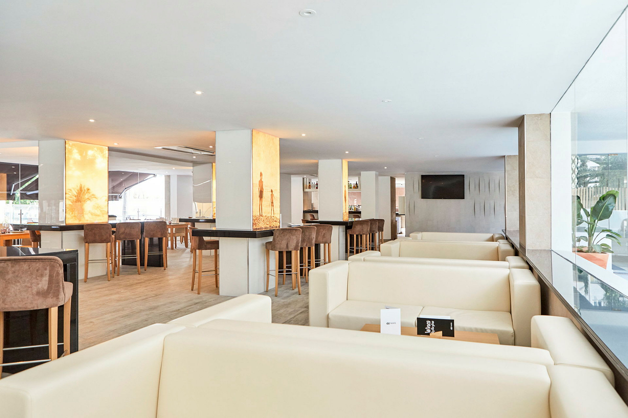Bilde av en moderne restaurantlounge med lyse møbler og barmøbler. (AI-generert tekst)