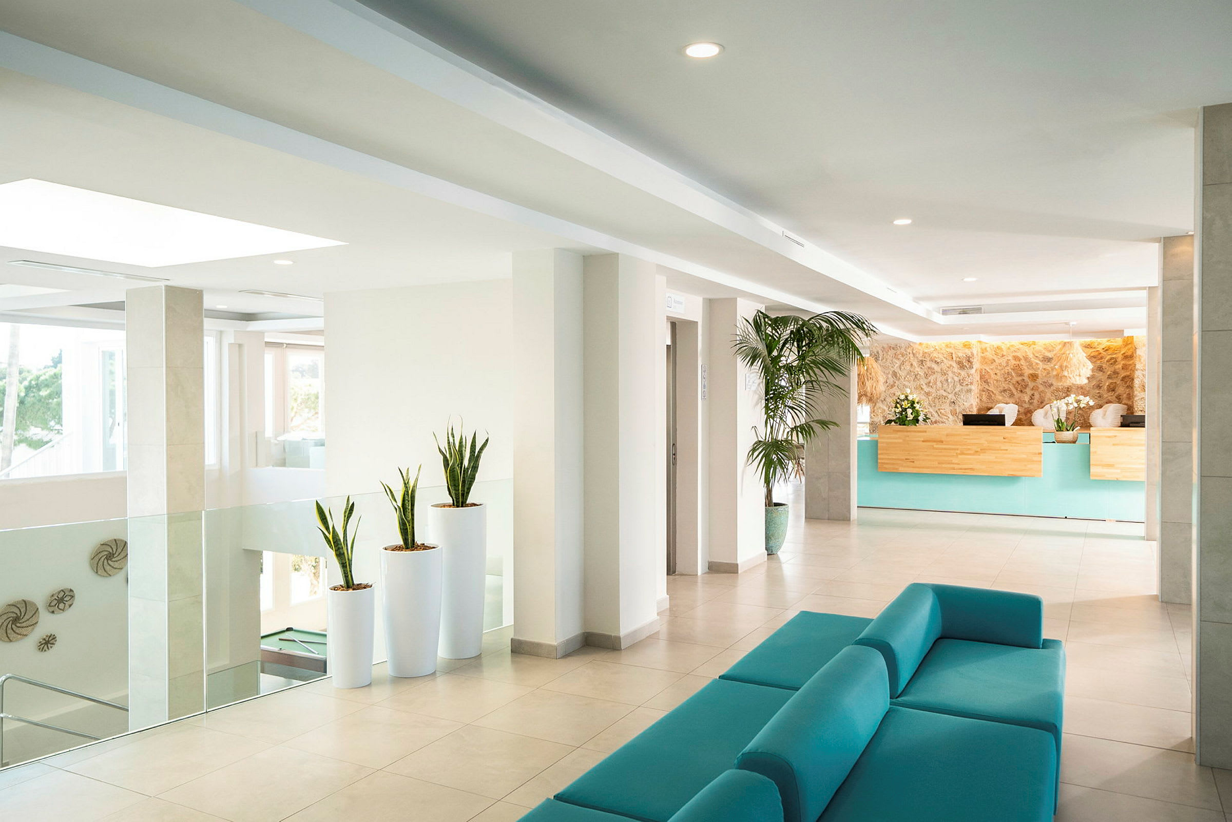Hotellobby med turkis sofa, resepsjon og dekorative planter. (AI-generert tekst)