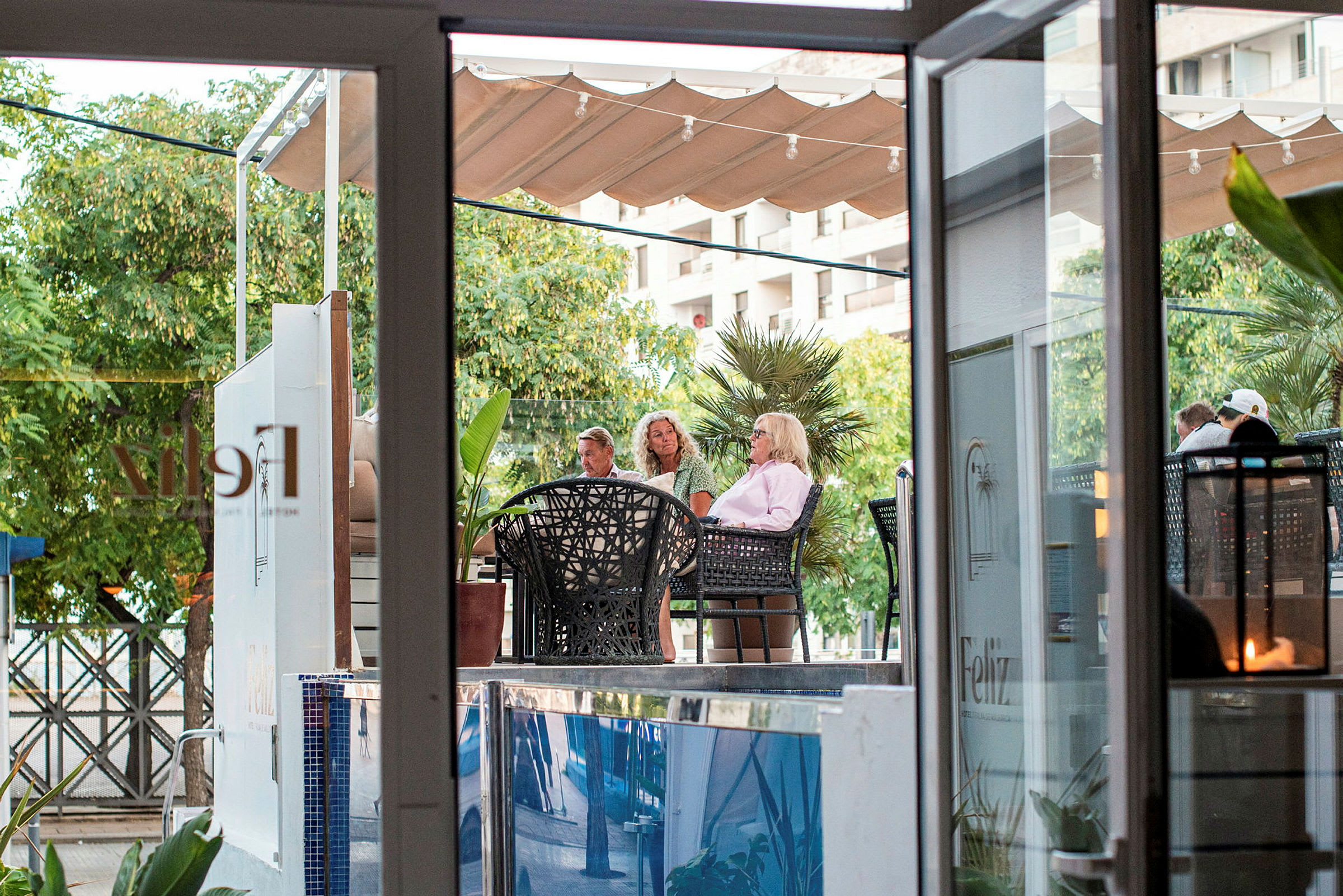 Personer sitter på en utendørskafé i grønne omgivelser. (AI-generert tekst)
