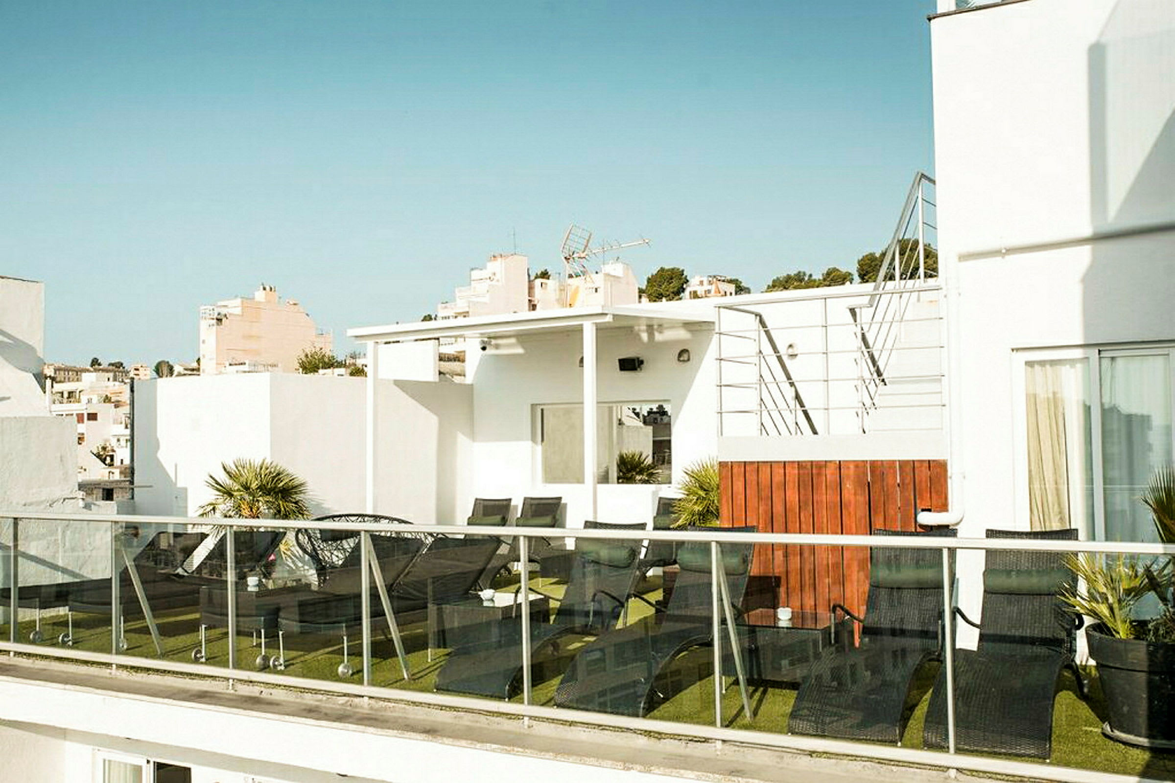 Bilde av en terrasse med solsenger og grønne planter. (AI-generert tekst)