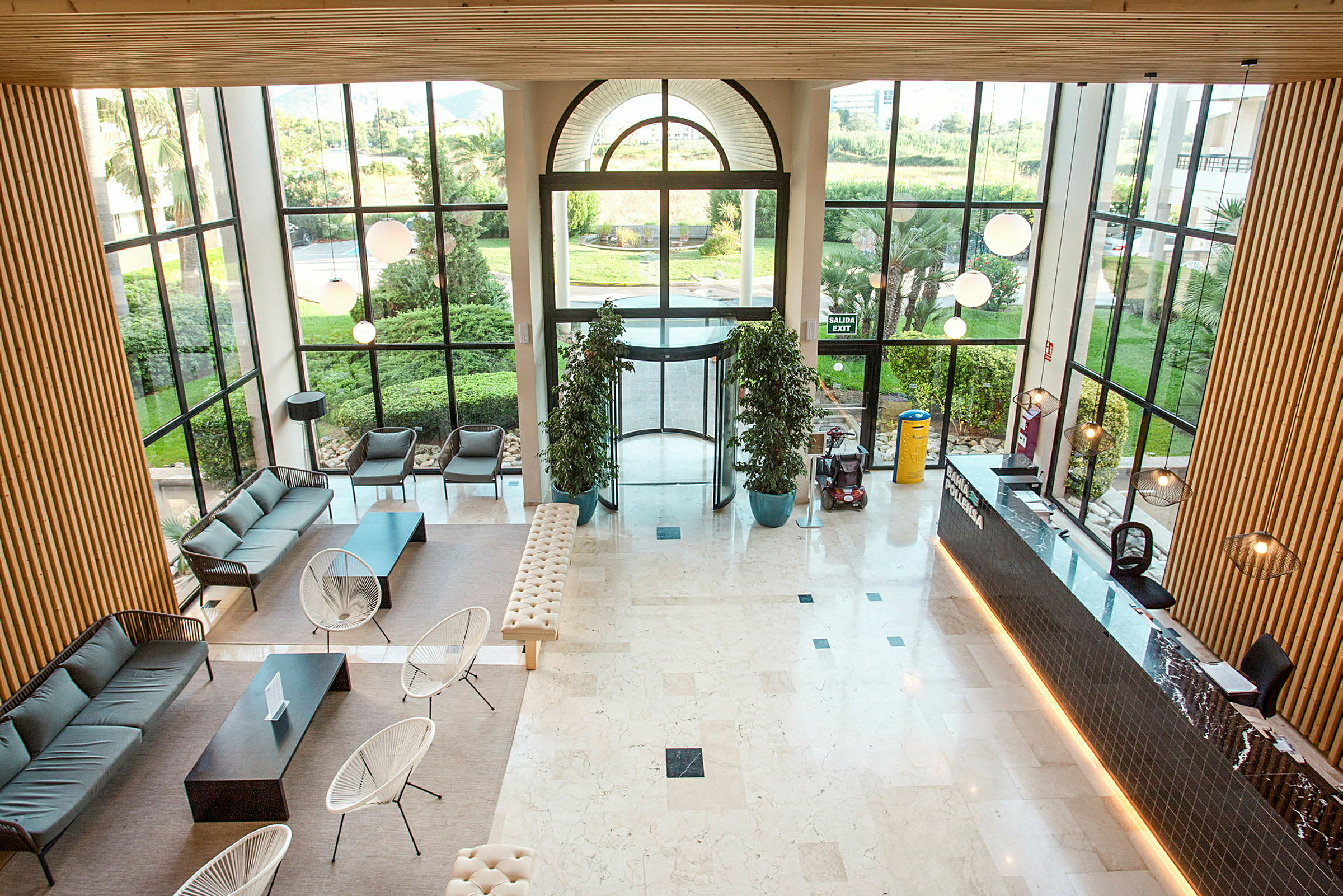 En moderne hotellobby med sittemøbler, resepsjonsdisk og store vinduer som slipper inn naturlig lys. (AI-generert tekst)