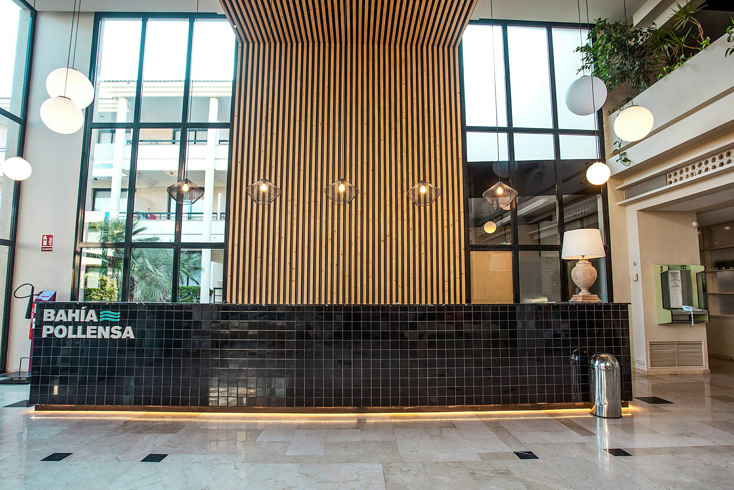 Resepsjonen på et hotell med en moderne innredning, en svart flislagt skranke og en vegg av tre bak. (AI-generert tekst)