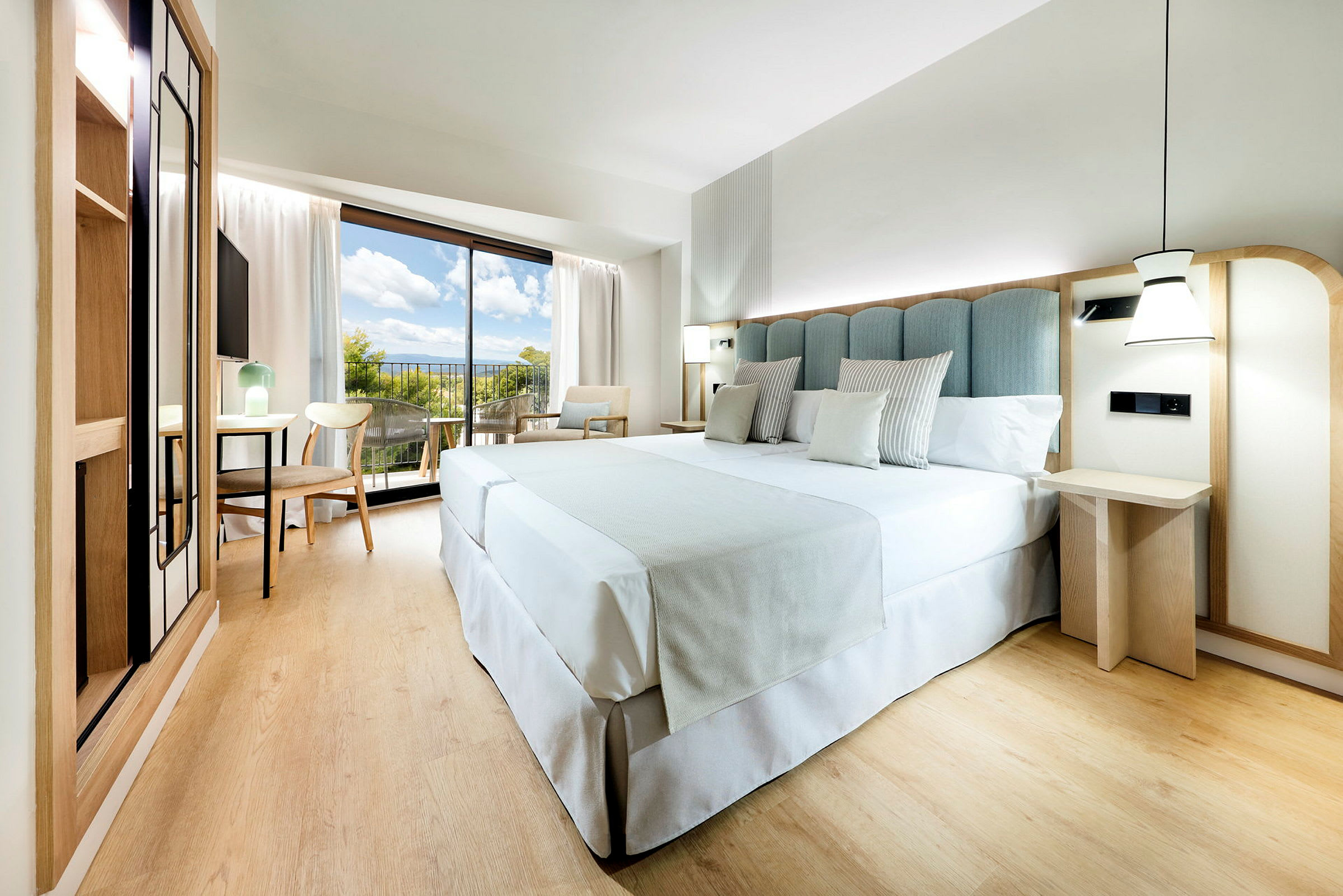 Et moderne hotellrom med en stor seng, tremøbler og en balkong med utsikt. (AI-generert tekst)