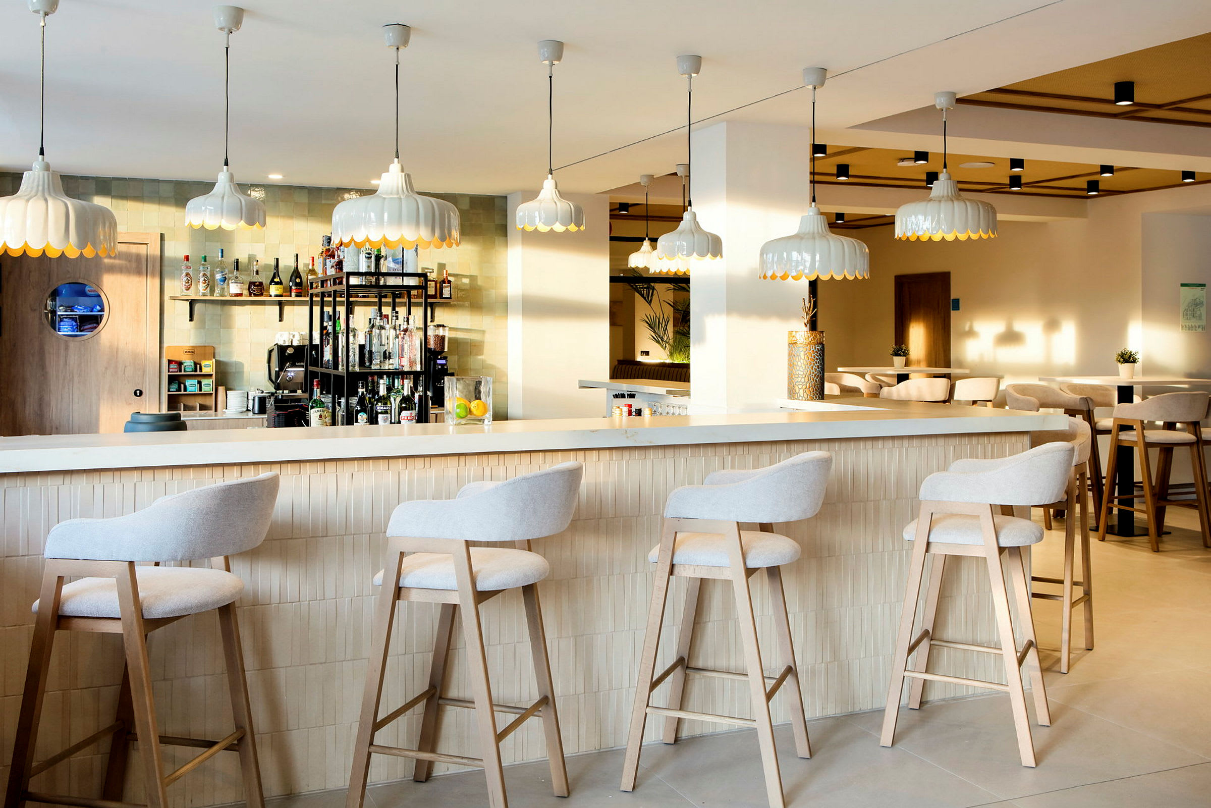 En moderne bar med høye stoler ved disken og stilige lamper som henger fra taket. (AI-generert tekst)