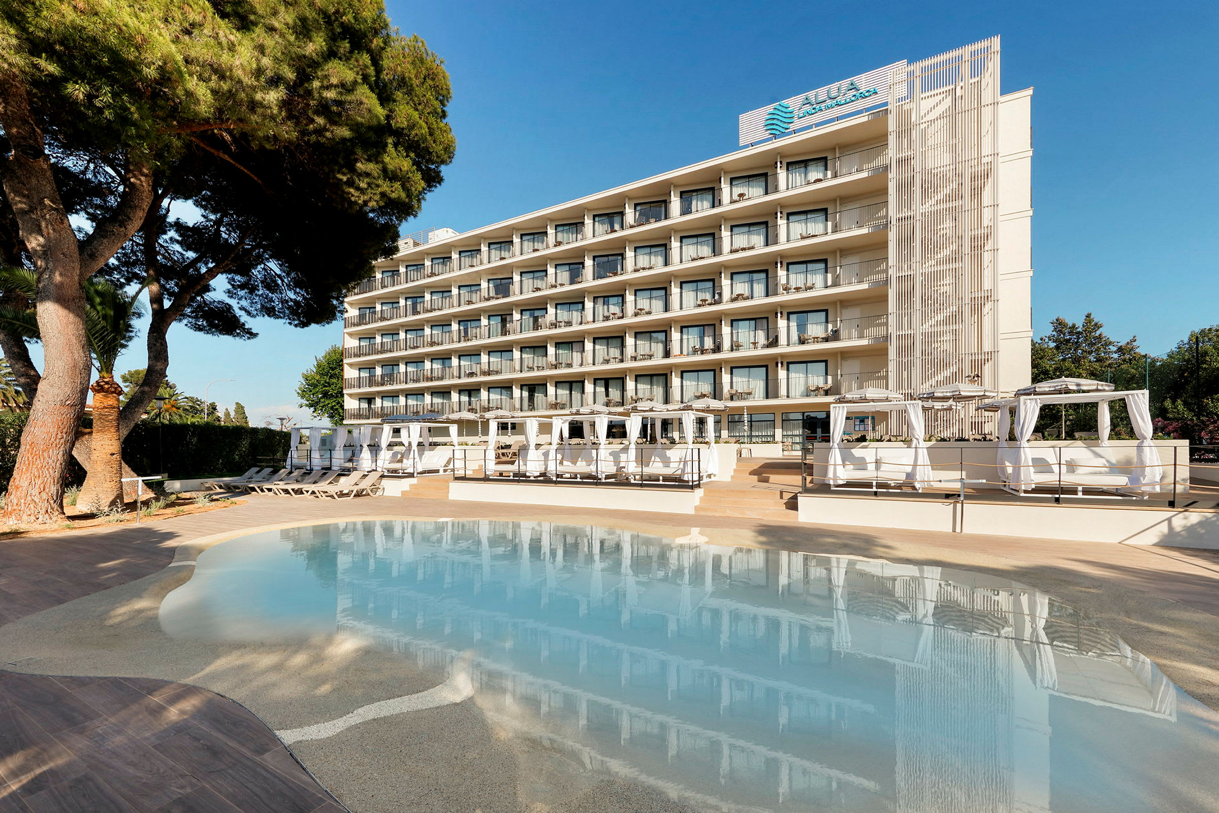 Et hotell sett fra bassengområdet med solsenger og cabanas. (AI-generert tekst)