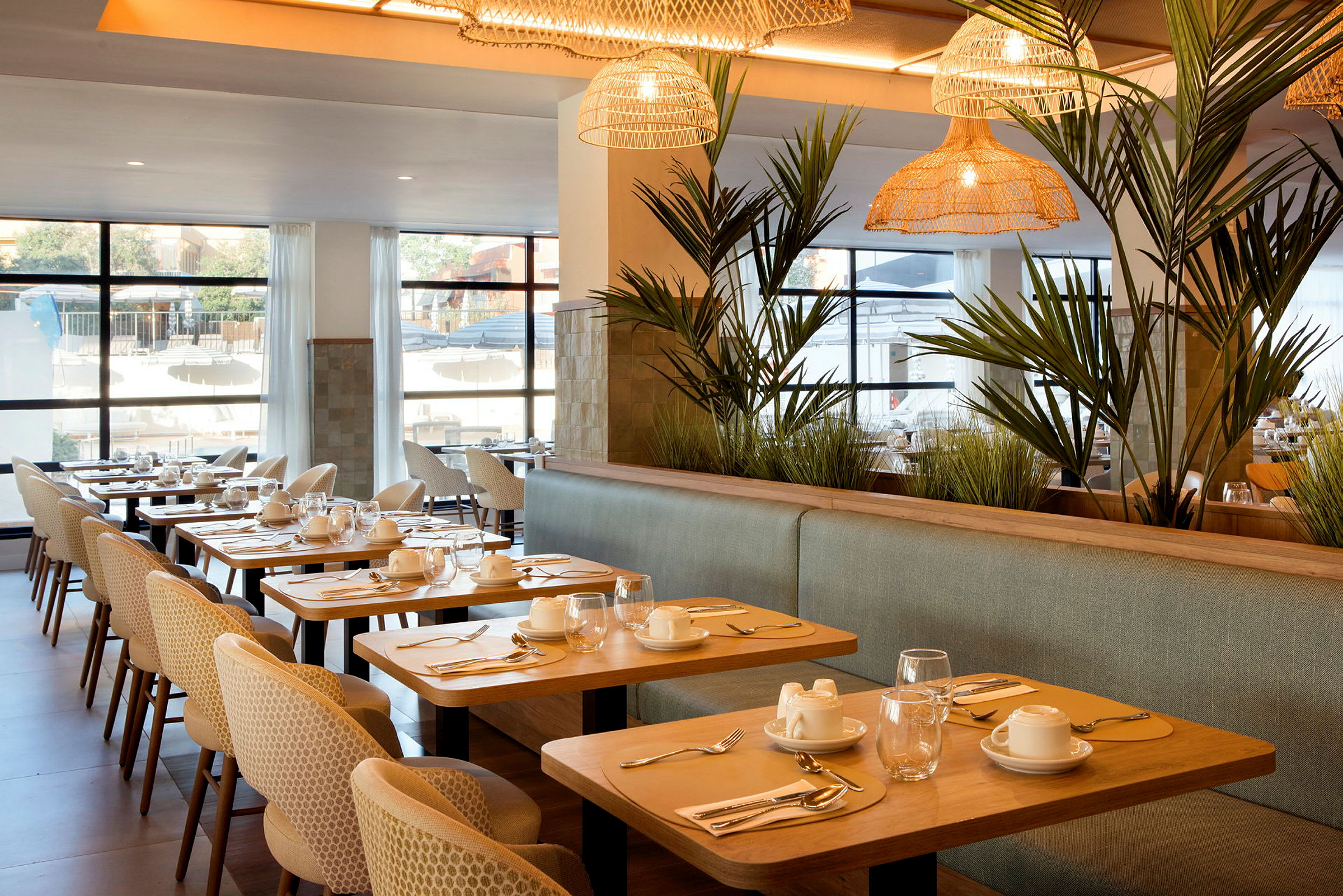 En elegant restaurant med dekkede bord, komfortable stoler og grønne planter som dekor. (AI-generert tekst)