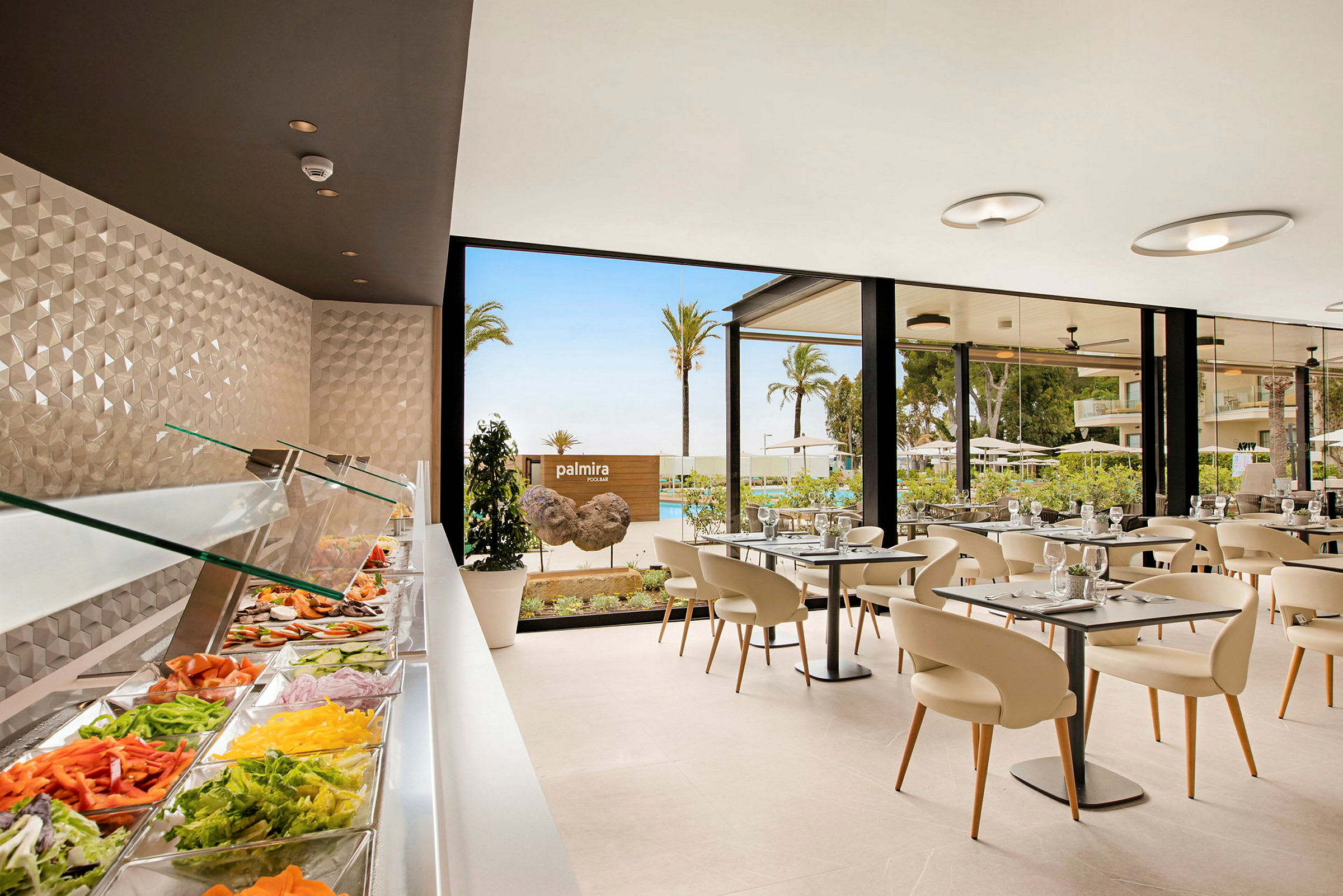 Buffet med grønnsaker i et glassforsynt serveringsområde, spiseplass med bord og stoler ved vinduer med utsikt over palmetrær og basseng. (AI-generert tekst)