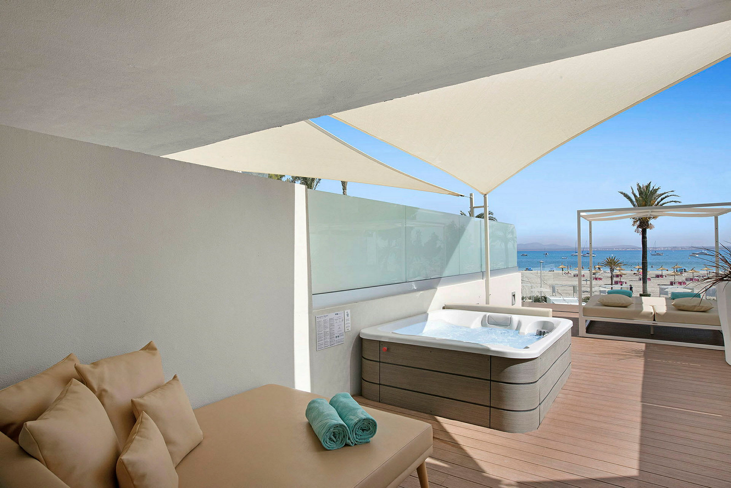 Et soldekk med en jacuzzi, solseng og utsikt mot stranden og havet. (AI-generert tekst)