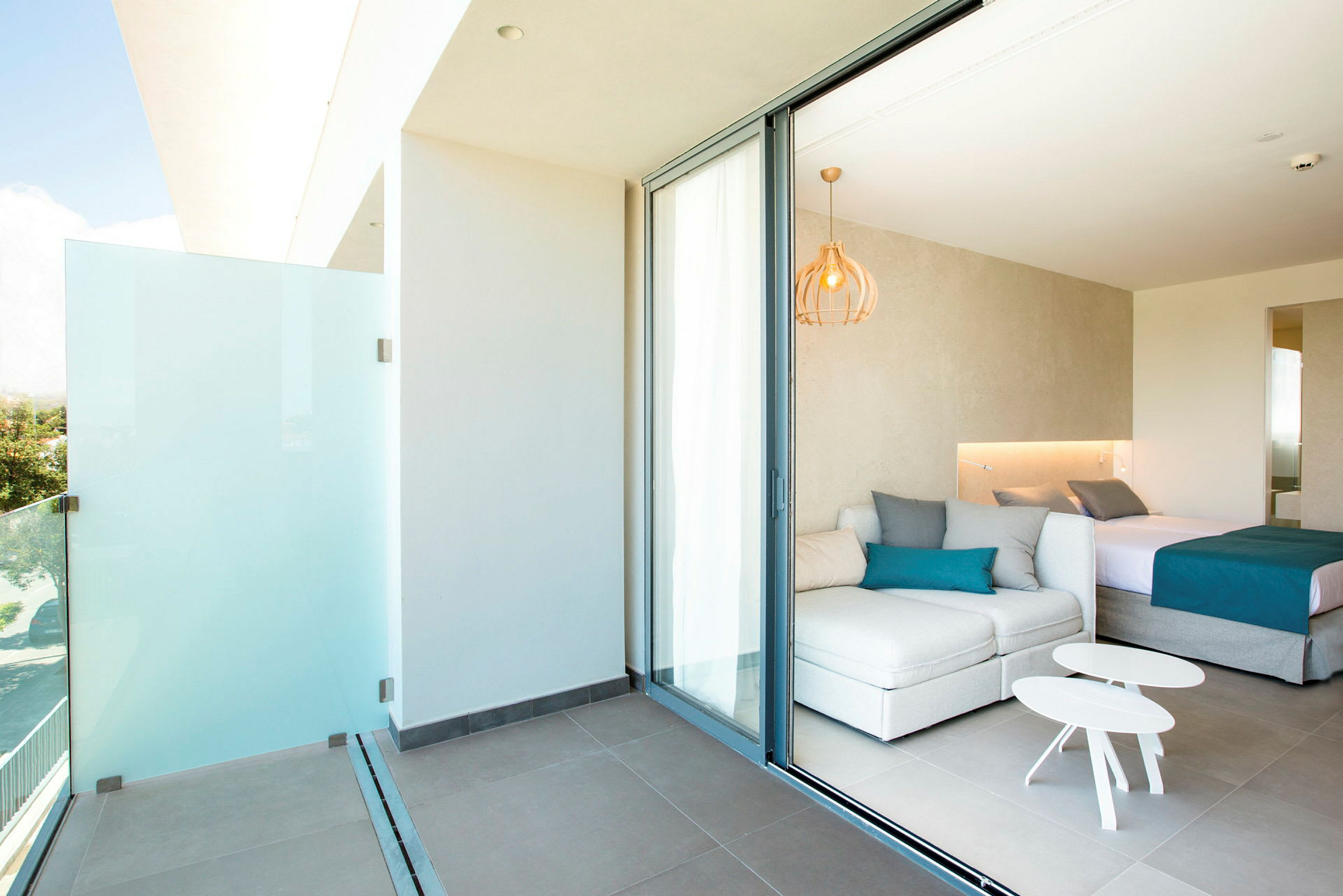 En moderne hotellsuite med balkong, hvite møbler og en dobbeltseng. (AI-generert tekst)