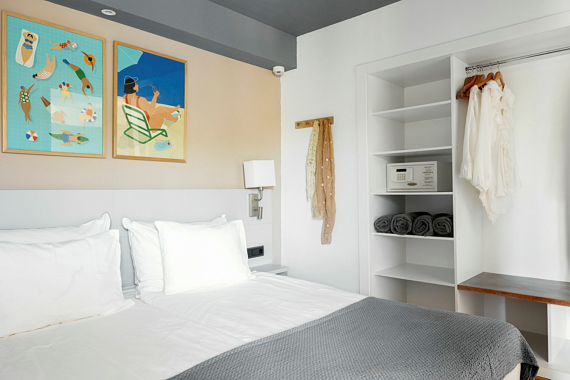 Et moderne hotellrom med en seng, vegghengte bilder og et åpent skap. (AI-generert tekst)