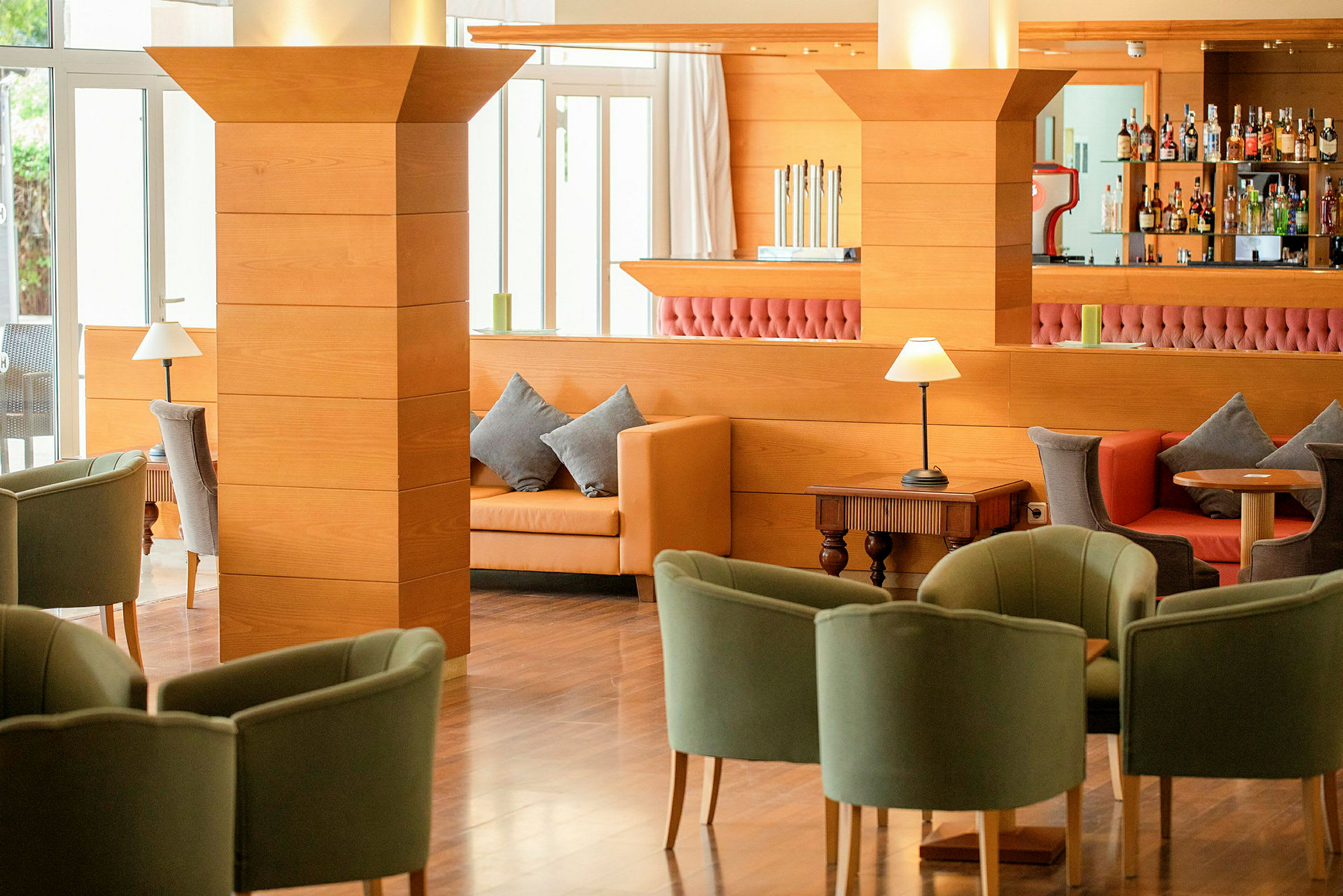 Interiør av en hotellounge med komfortable sitteplasser, treinteriør og en bar i bakgrunnen. (AI-generert tekst)