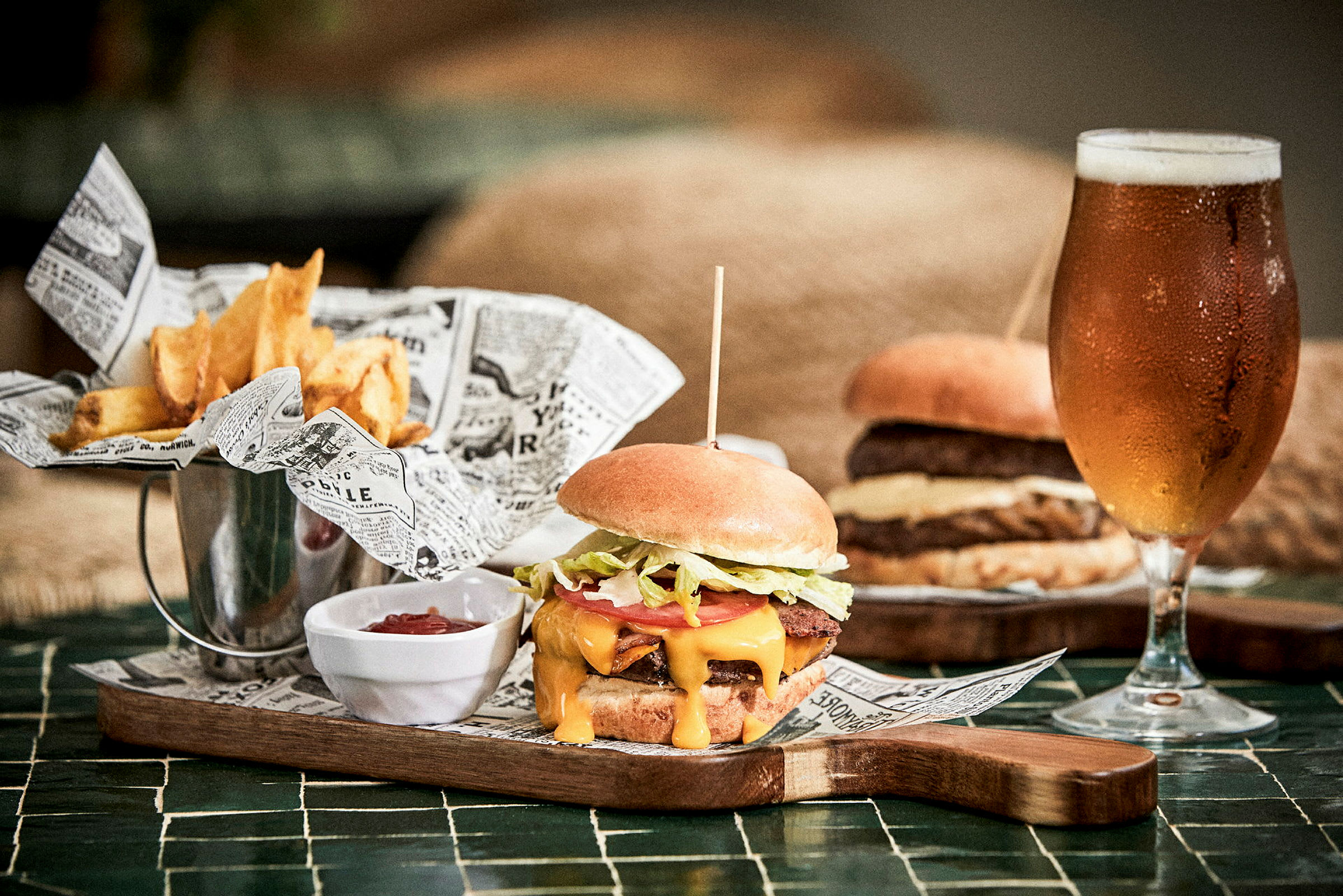 Bilde av en hamburgertallerken med pommes frites, ketchup og et glass øl. (AI-generert tekst)
