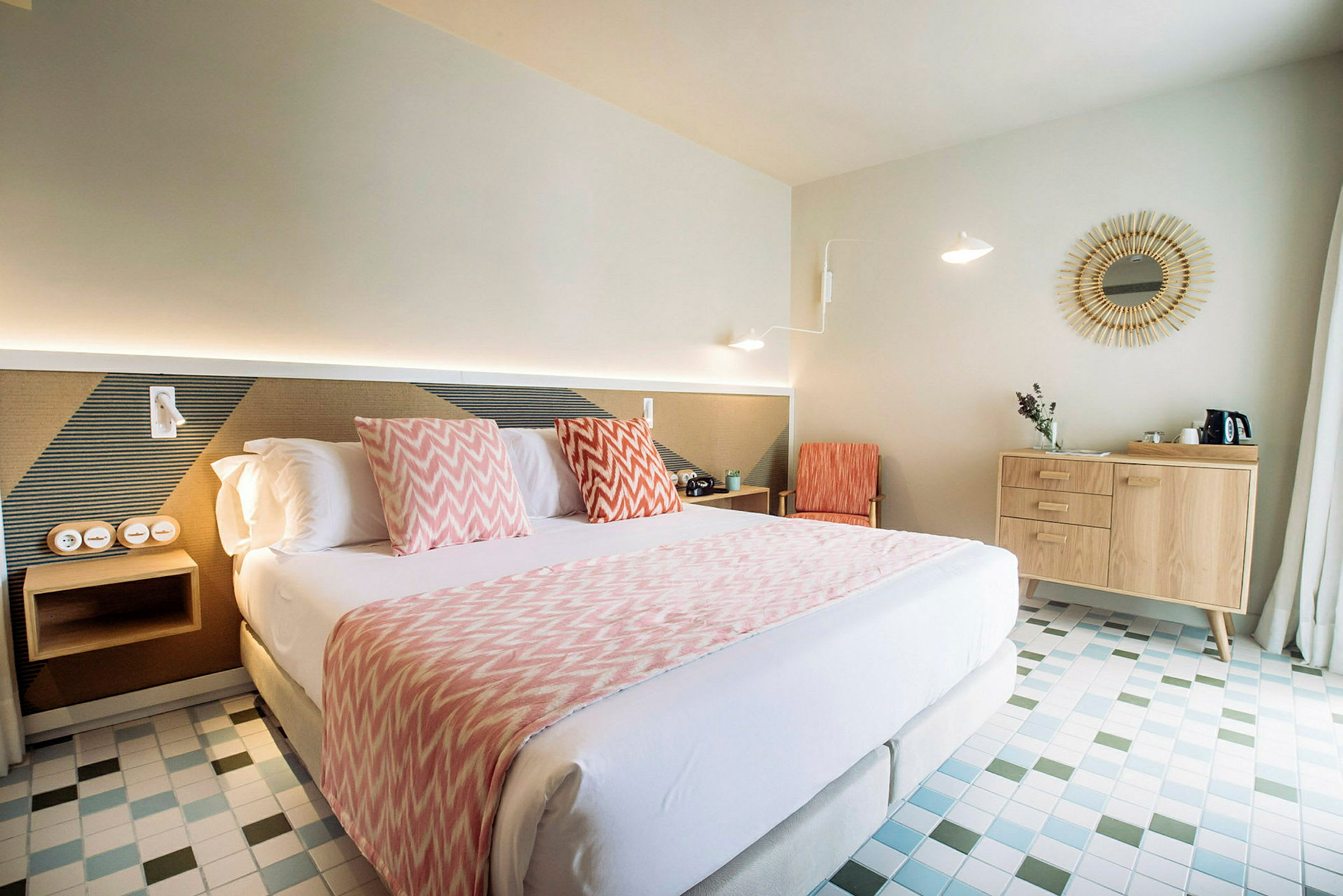 Et lyst hotellrom med to enkeltsenger eller dobbeltseng, dekorative puter og en trekommode ved siden. (AI-generert tekst)